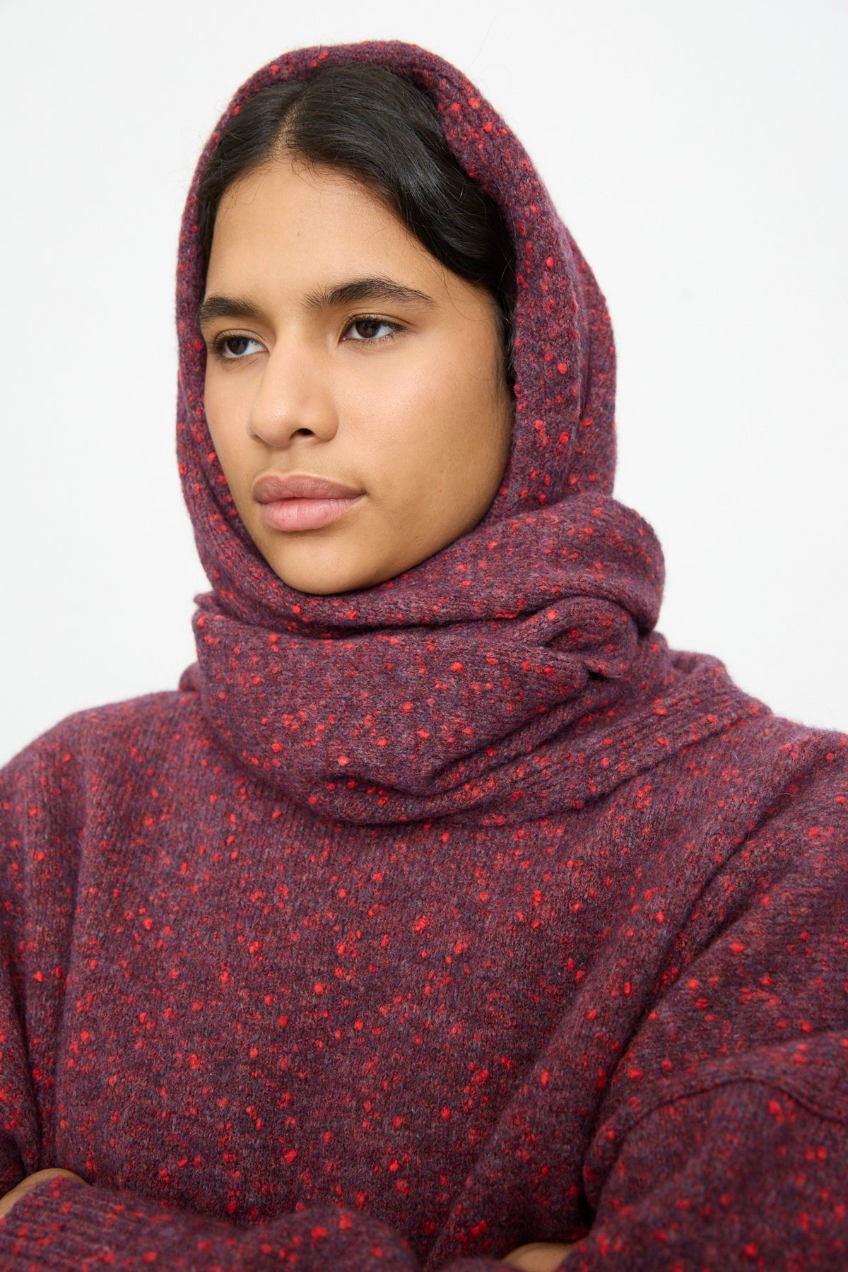 A person wearing a dark red, speckled finish Maxi Bandana in Beaujolais layered over a matching cotton blend sweater.