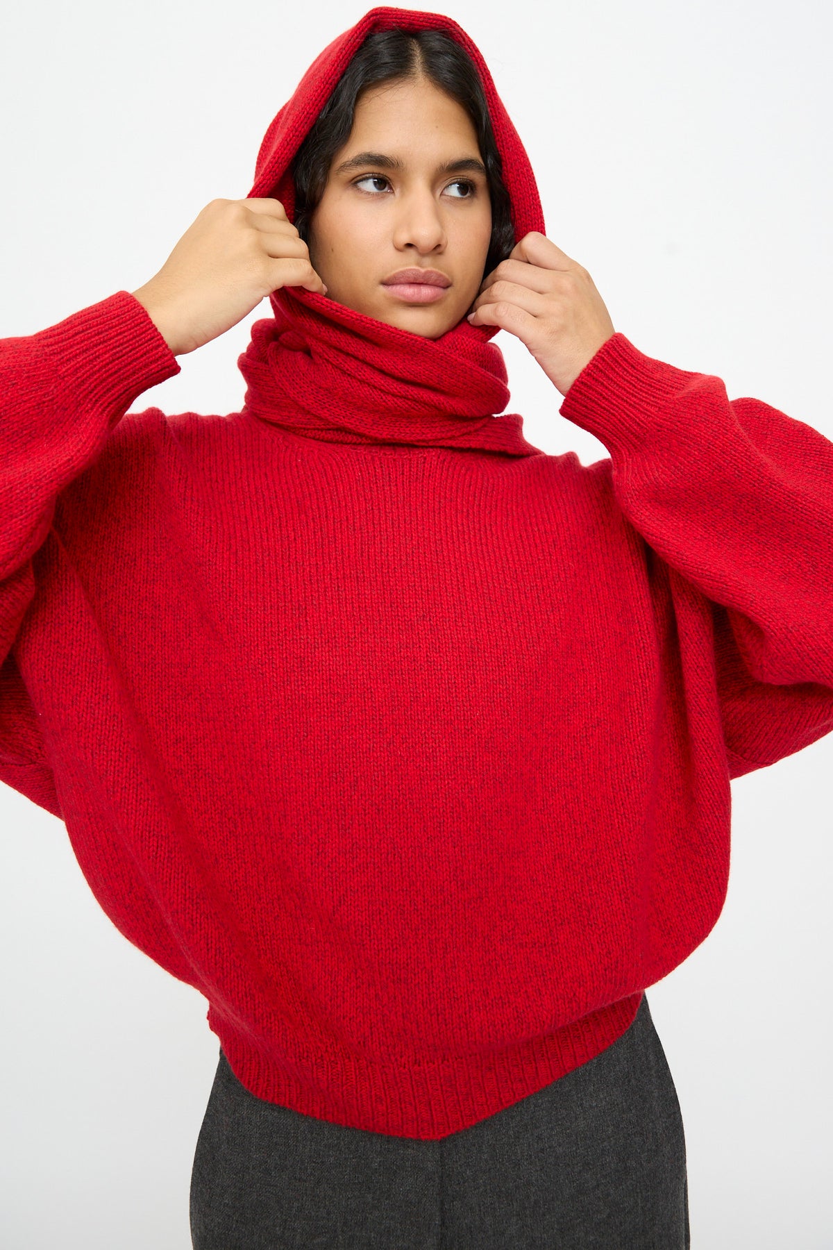 A person wearing a bright red knit sweater and a matching Cordera Merino and Cashmere Maxi Bandana in Red wrapped around their neck.