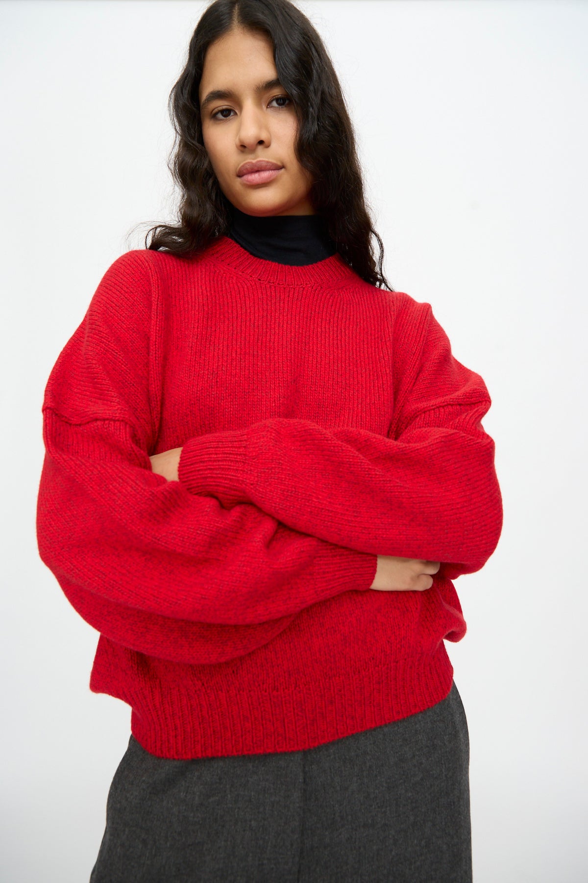 Person wearing a red Merino and Cashmere Sweater with an oversized fit, dropped shoulders, and long, cuffed batwing sleeves.