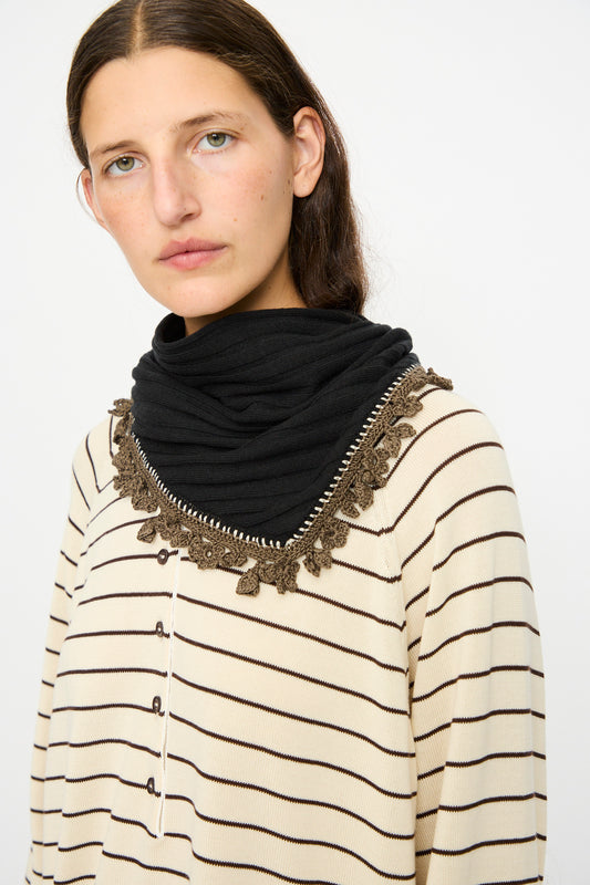 A woman wears the Cordera Merino Wool Bandana in Black and a cream and black striped top with crochet lace trim, standing against a plain white background.