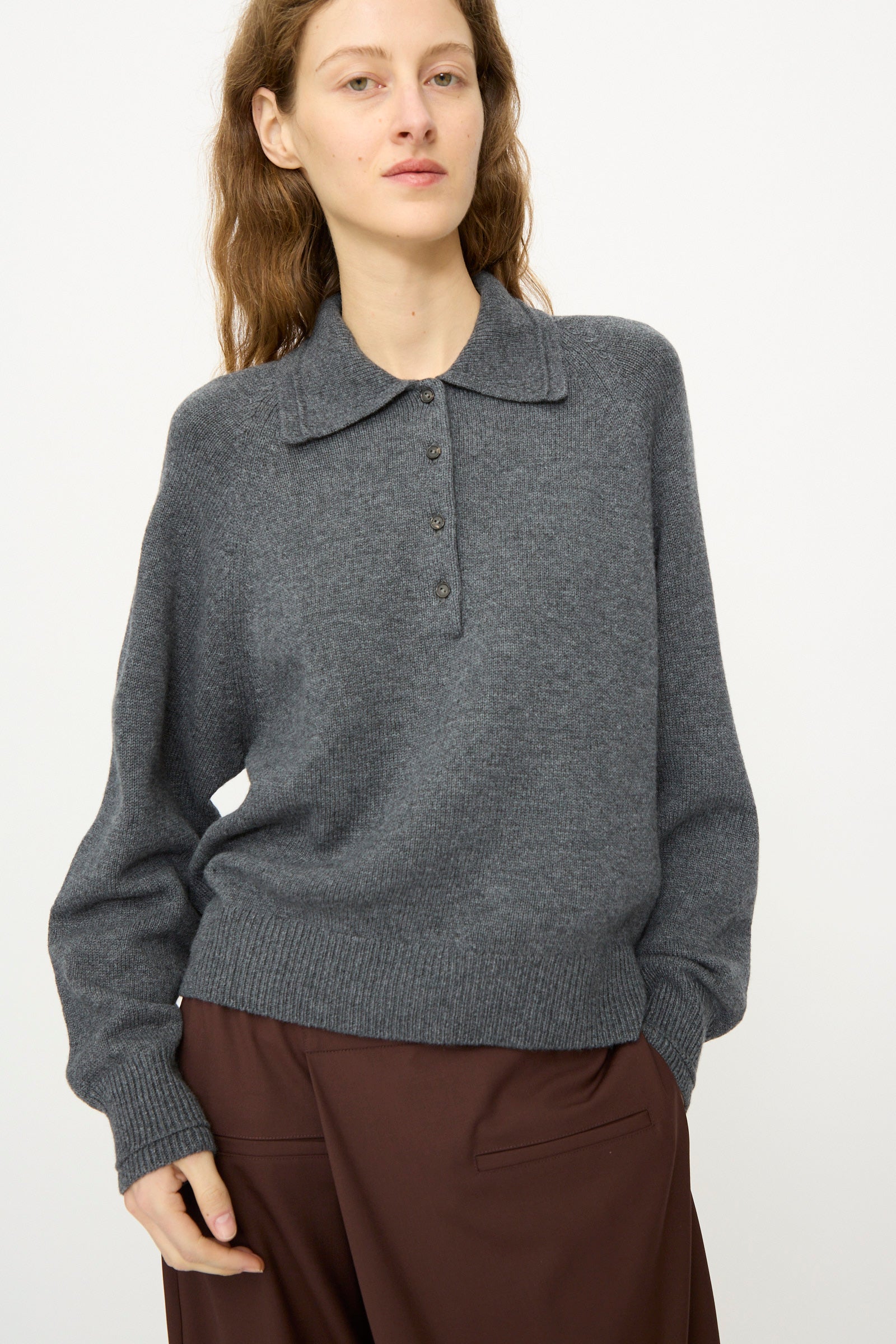 A person wears the Cordera Merino Wool Polo Sweater in Grey with brown pants, standing against a plain white background.
