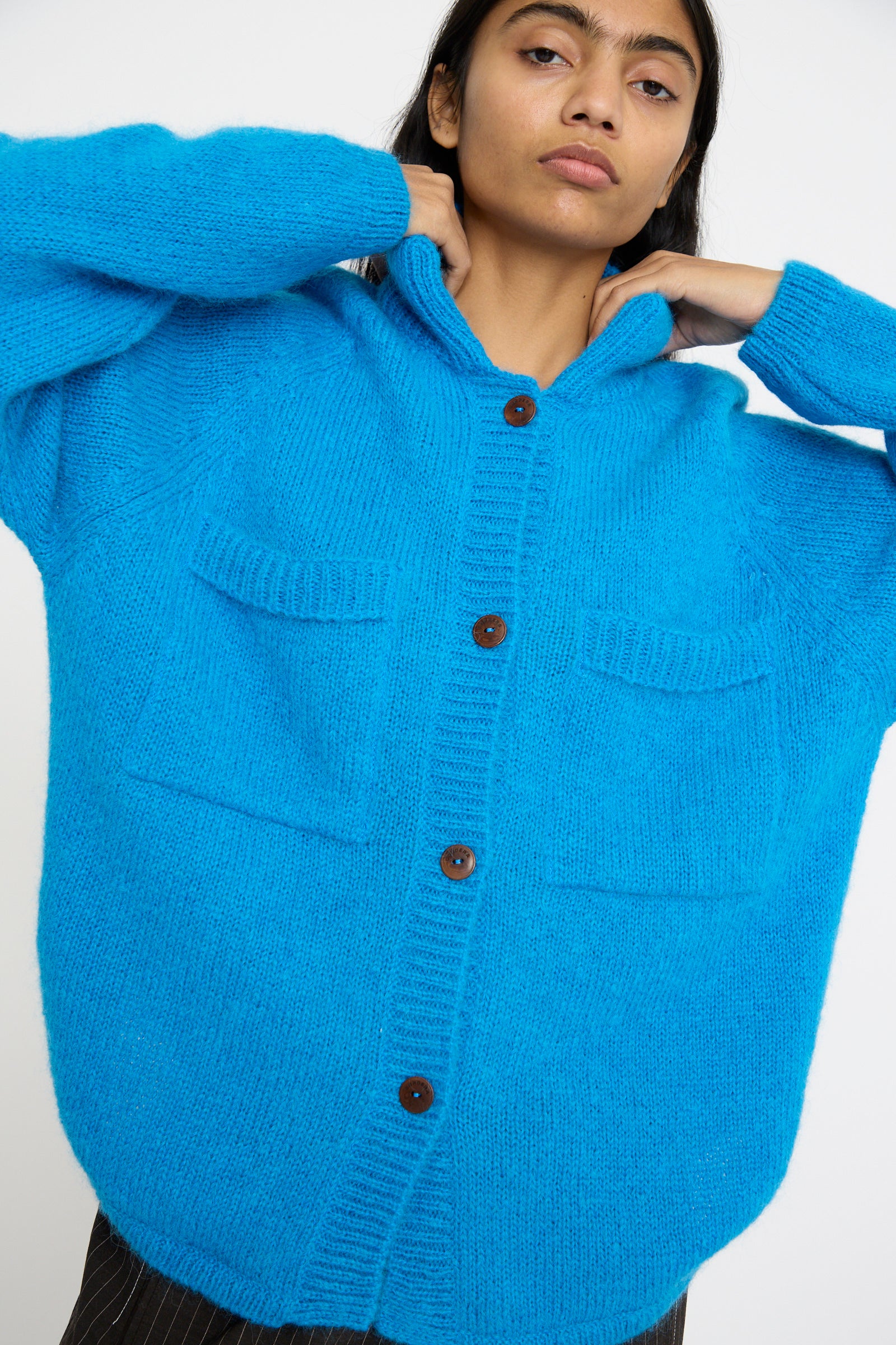 Person wearing the Cordera Mohair and Baby Alpaca Polo Jacket in Cerúleo, a bright blue cardigan with button-up design and pockets.