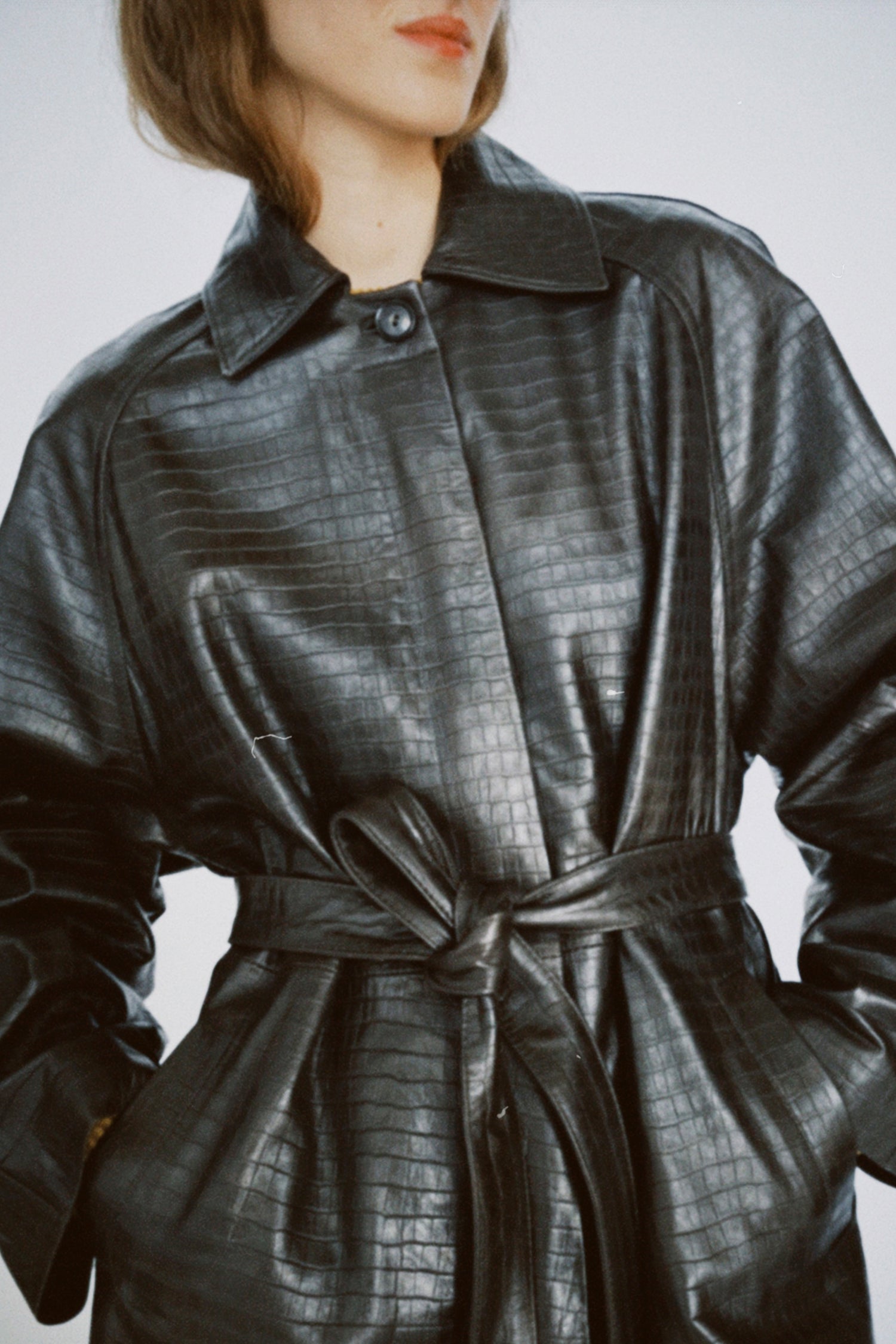 A woman wearing Cordera's Nappa Long Coat in Crocodile against a white background.