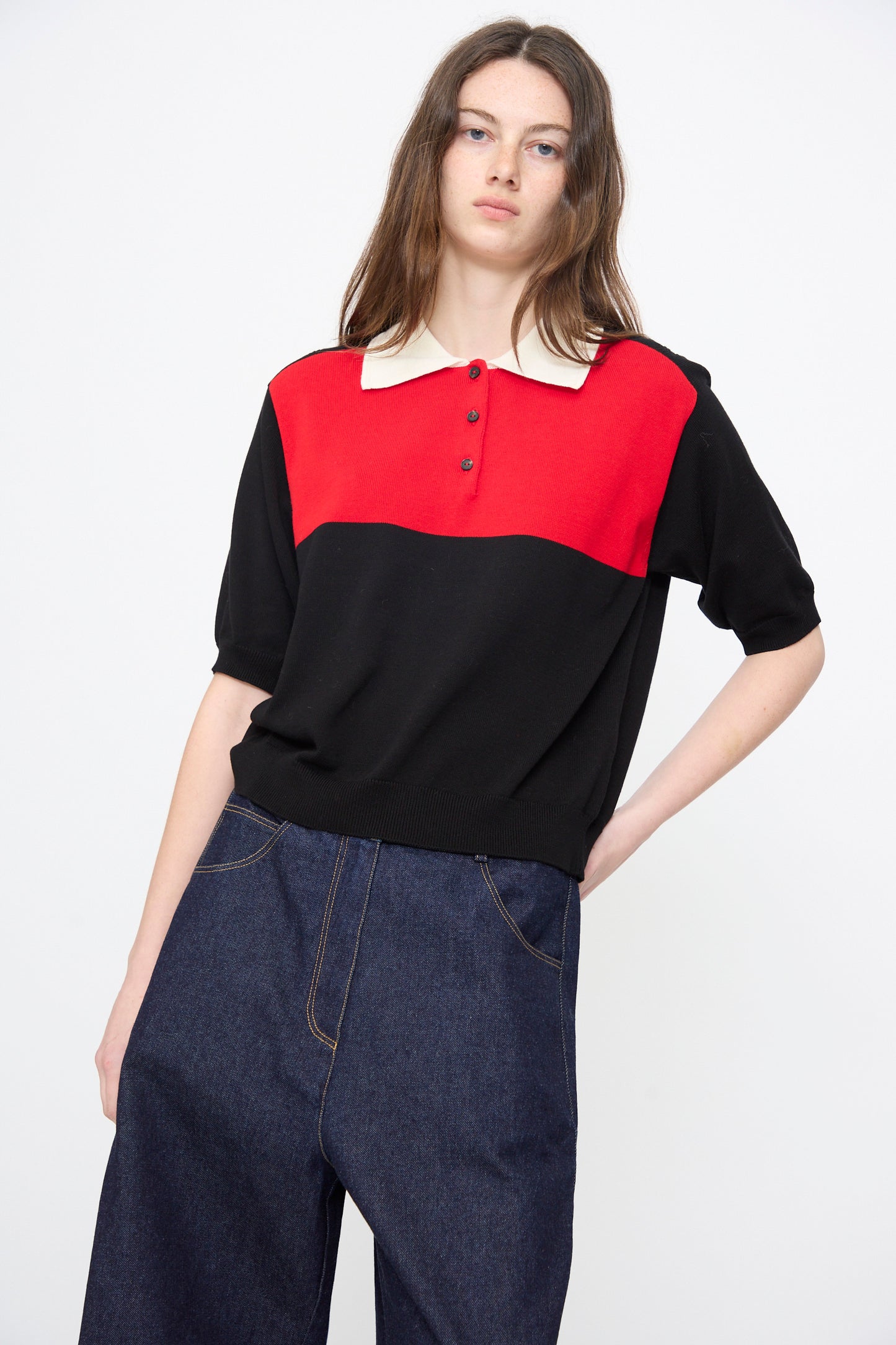 A person wears Cordera's Cotton Polo in Colorblock with a white collar and relaxed fit, paired with high-waisted dark blue wide-leg jeans, standing against a plain white background.