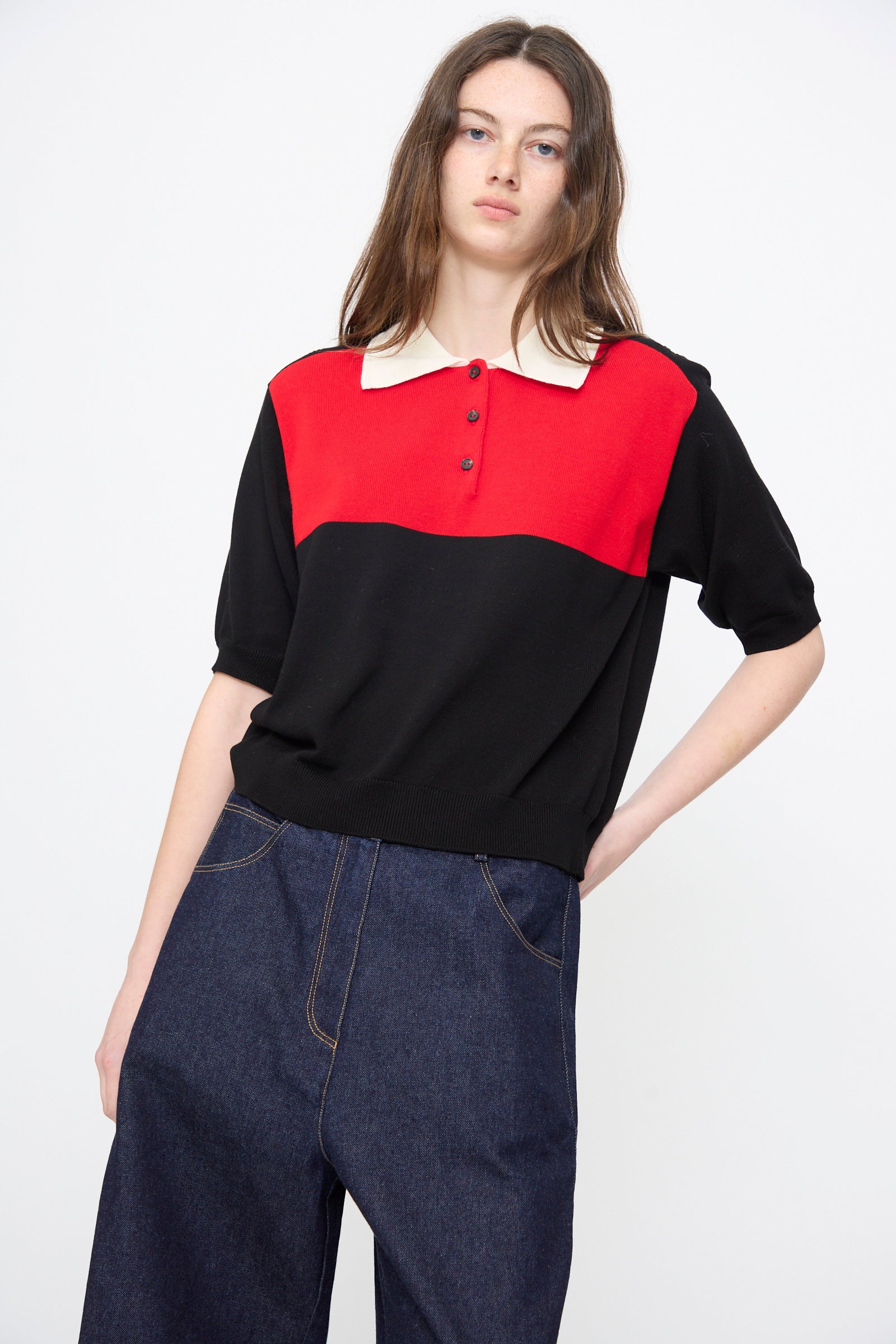 A person wears Cordera's Cotton Polo in Colorblock with a white collar and relaxed fit, paired with high-waisted dark blue wide-leg jeans, standing against a plain white background.