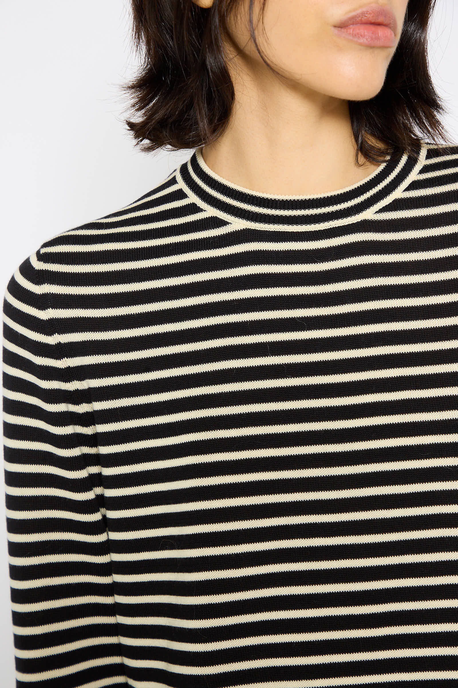 Person with shoulder-length dark hair wearing a Cordera Organic Cotton T-Shirt in Striped, photographed from the shoulders up.