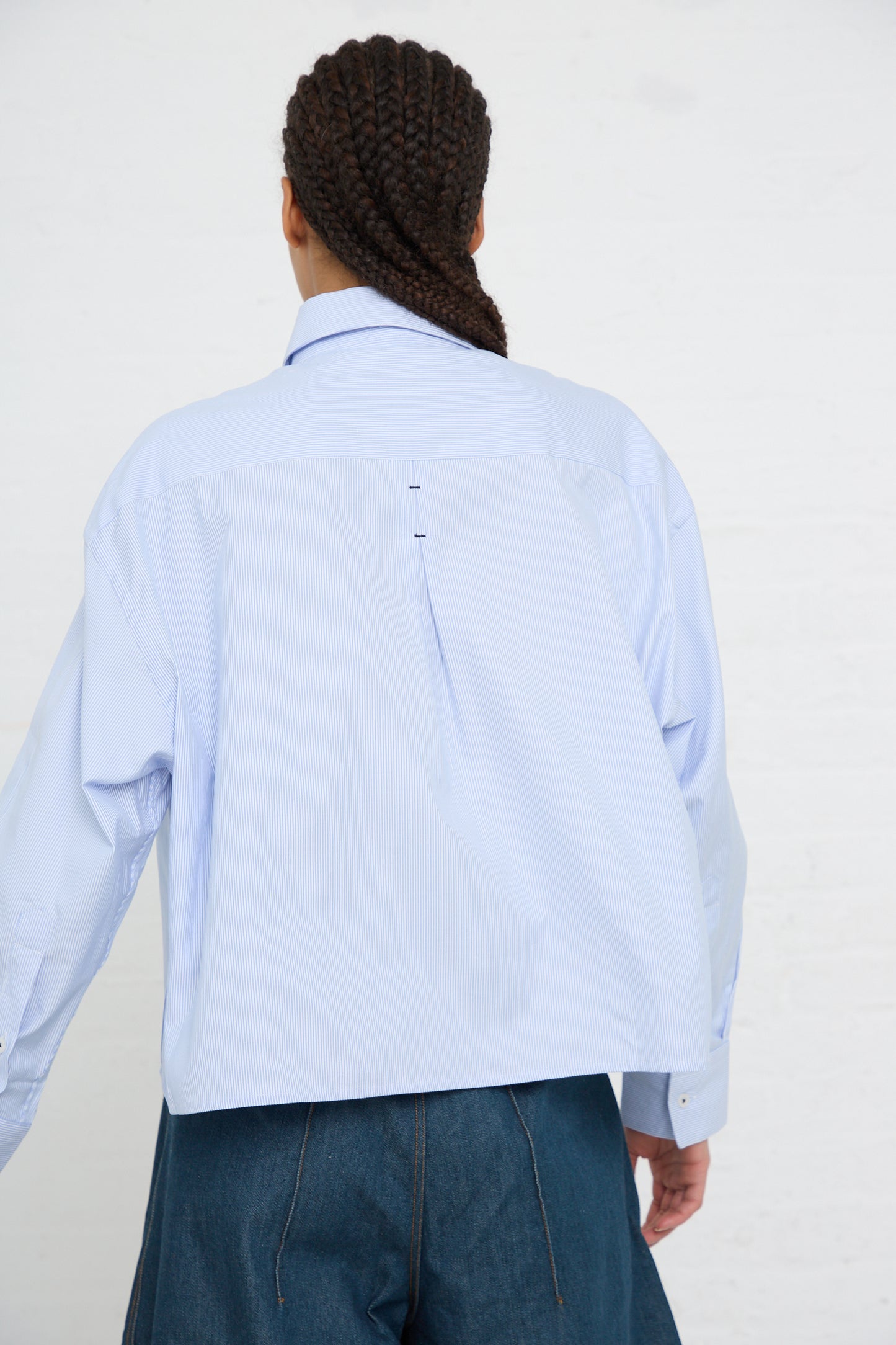 A person seen from behind wearing an Cordera Organic Oxford Shirt in Blue with an oversized fit and denim jeans.