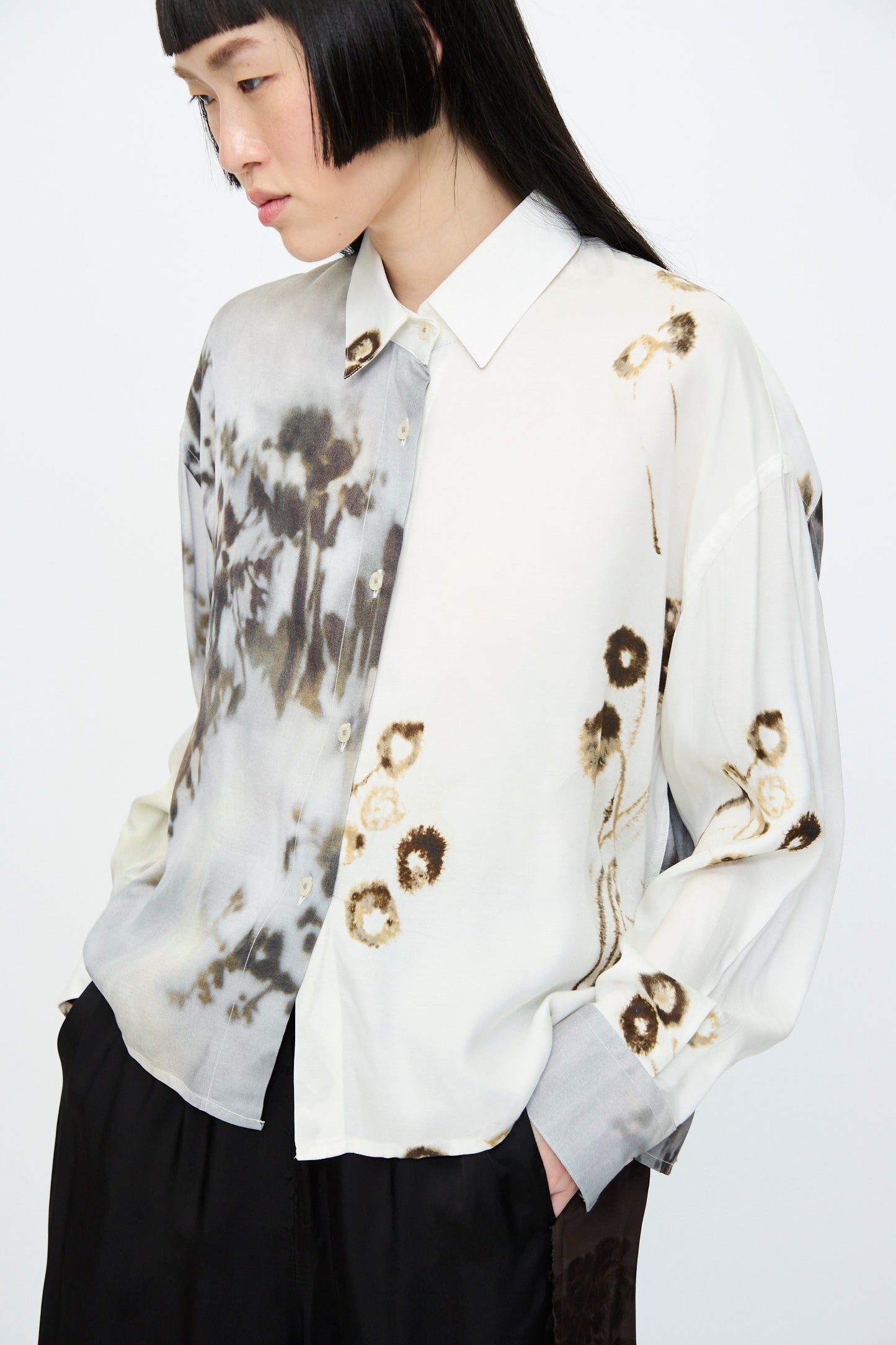 A person wearing Cordera's Printed Classic Shirt in Bicolor with a white and black floral pattern and oversized fit, looking to the side.