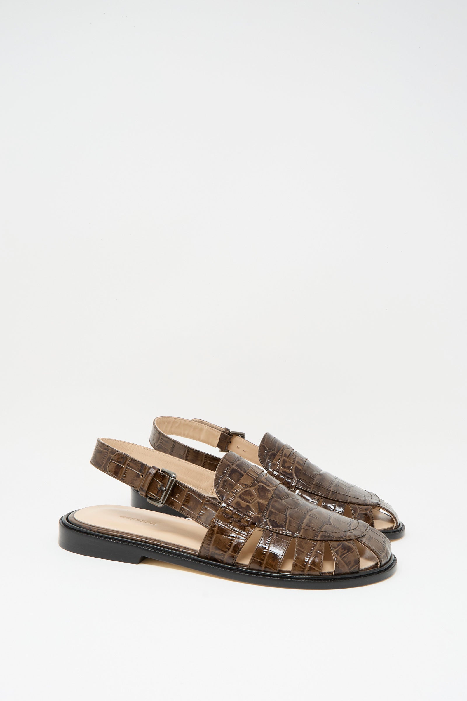 The Cordera Slingback Loafer in Crocodile features brown crocodile-pattern leather, closed toes, flat black soles, and a slingback design, shown against a plain white background.