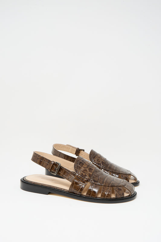 The Cordera Slingback Loafer in Crocodile features brown crocodile-pattern leather, closed toes, flat black soles, and a slingback design, shown against a plain white background.