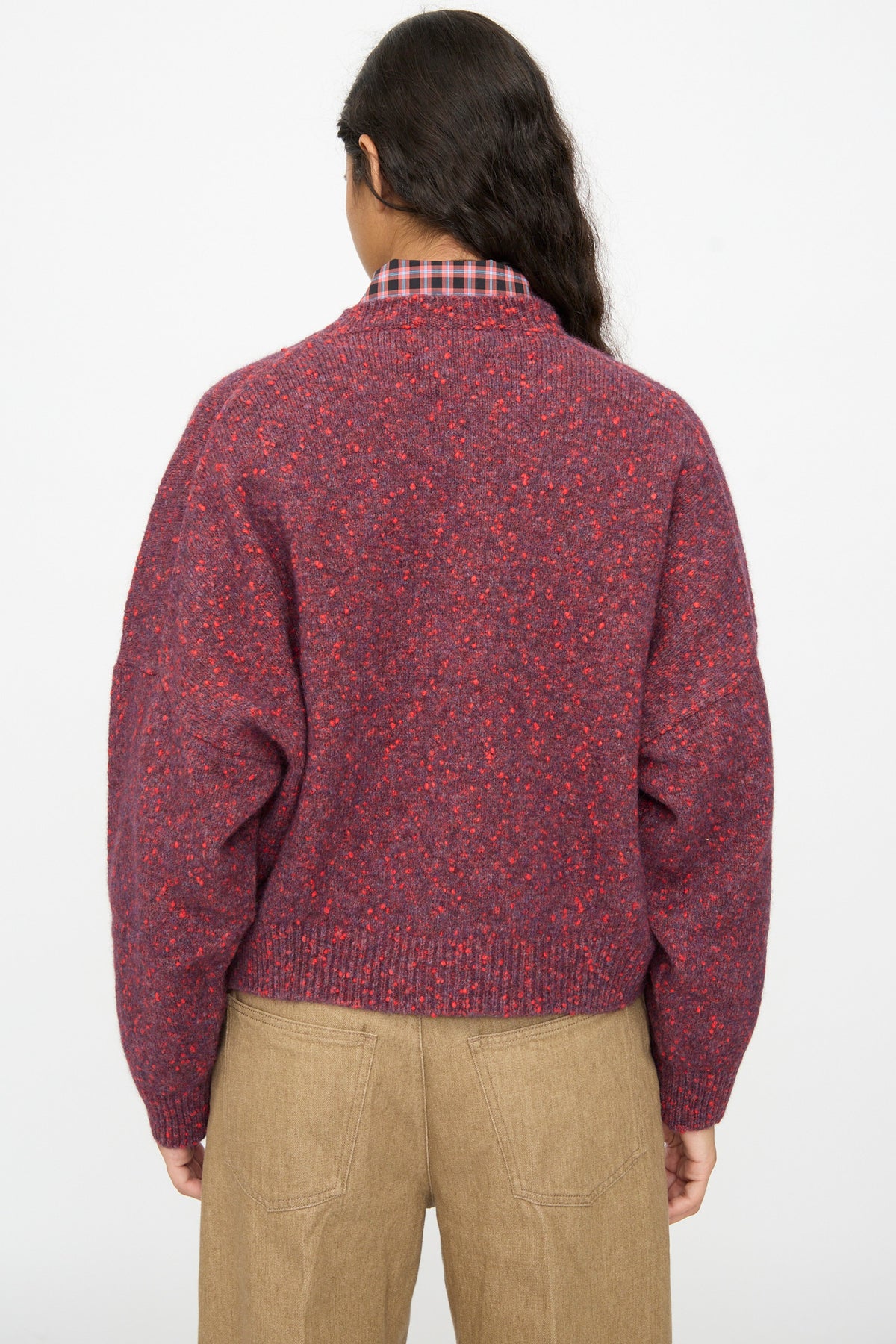Back view of a person wearing a maroon Speckled Crewneck Sweater in Beaujolais over a plaid collared shirt and tan pants.