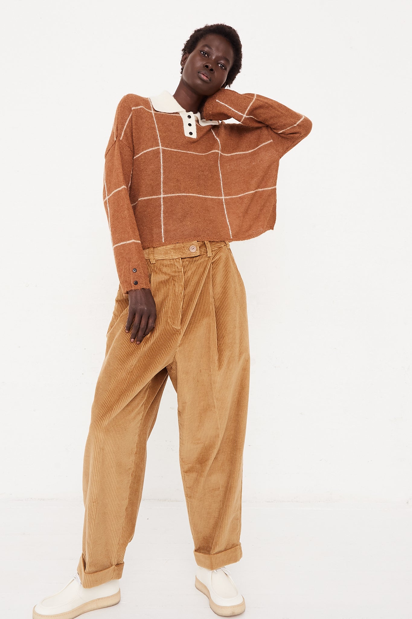 A model wearing a mid waist pant in a cotton corduroy. Features an elasticized waist in back, front pleat details, and wide leg. Designed by Cordera - Oroboro Store