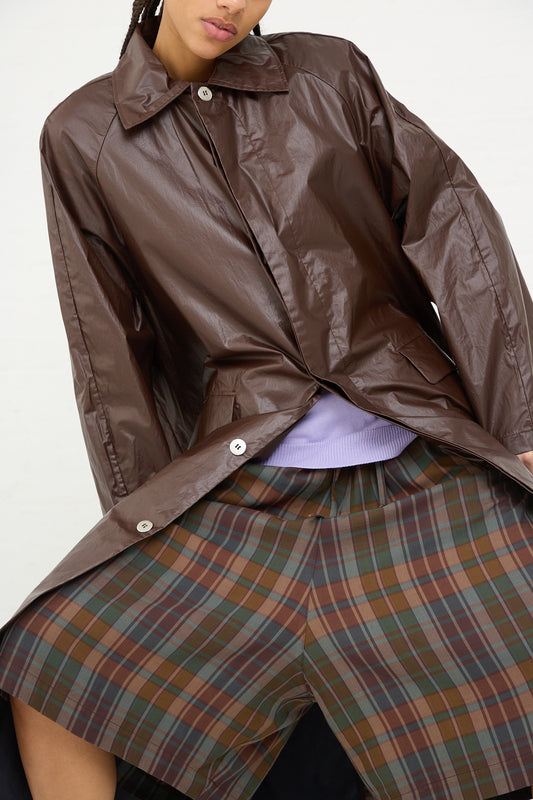 Woman wearing a water-repellent Cordera trench coat in Prune made in Spain and a plaid skirt.