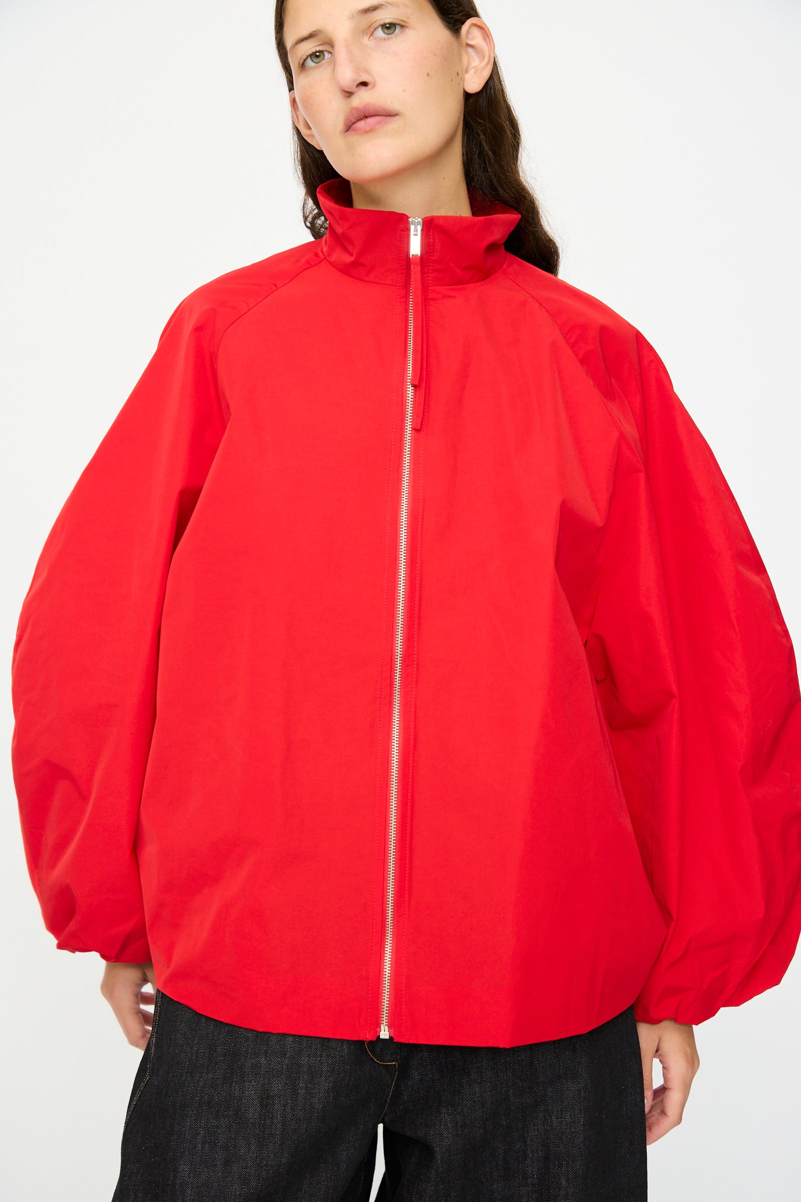 A person wears the Cordera Utility Balloon Jacket in Red, featuring a relaxed fit and balloon sleeves, paired with dark pants and standing against a plain white background.