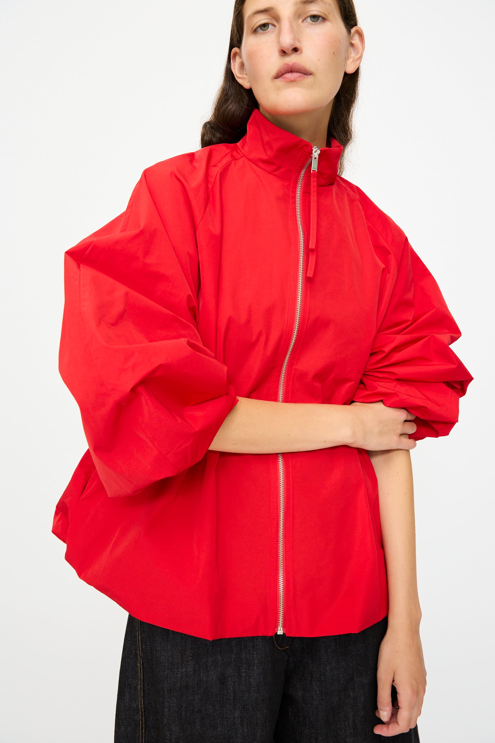 A person is wearing the Cordera Utility Balloon Jacket in Red, featuring voluminous sleeves, paired with dark pants, and standing against a plain white background.
