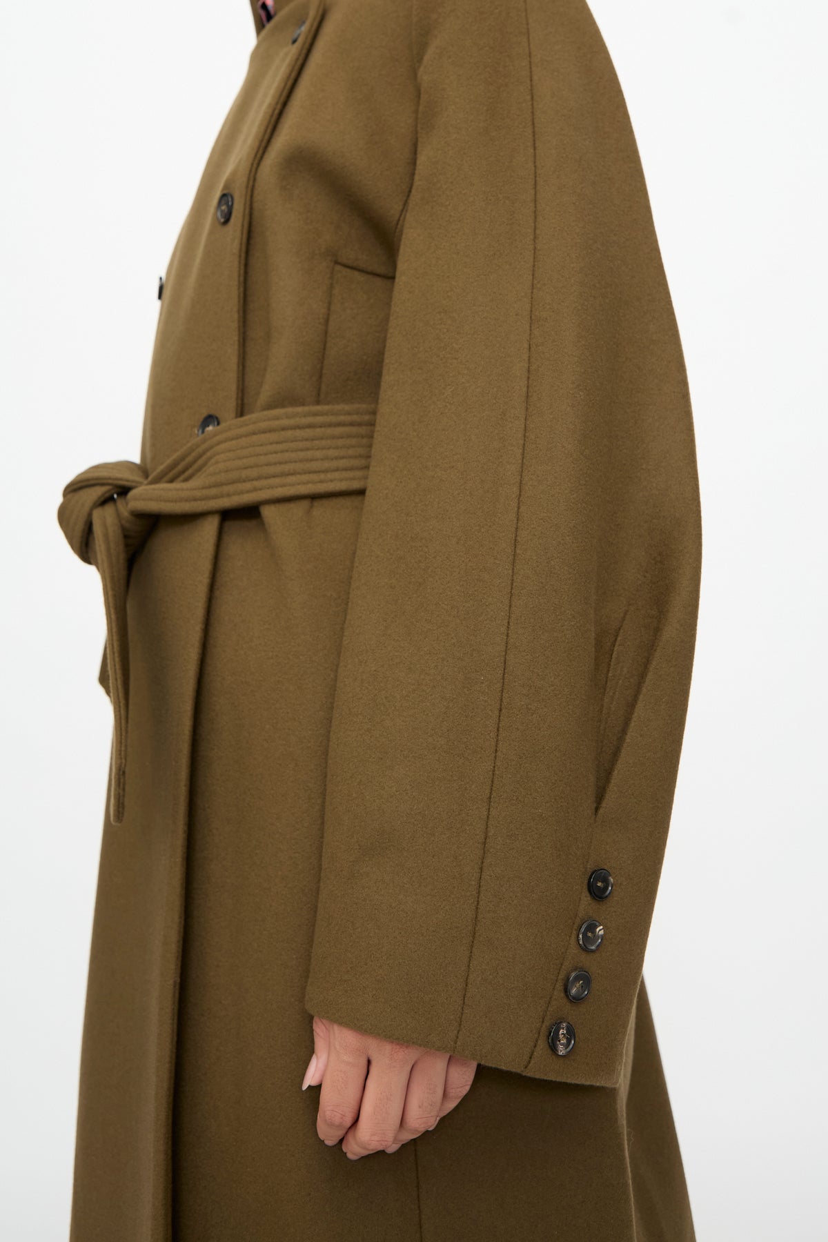 Side view of a Cordera Virgin Wool Long Coat in Pardo, featuring an oversized olive wool design with a mandarin collar, a tie waist, and buttoned cuffs.