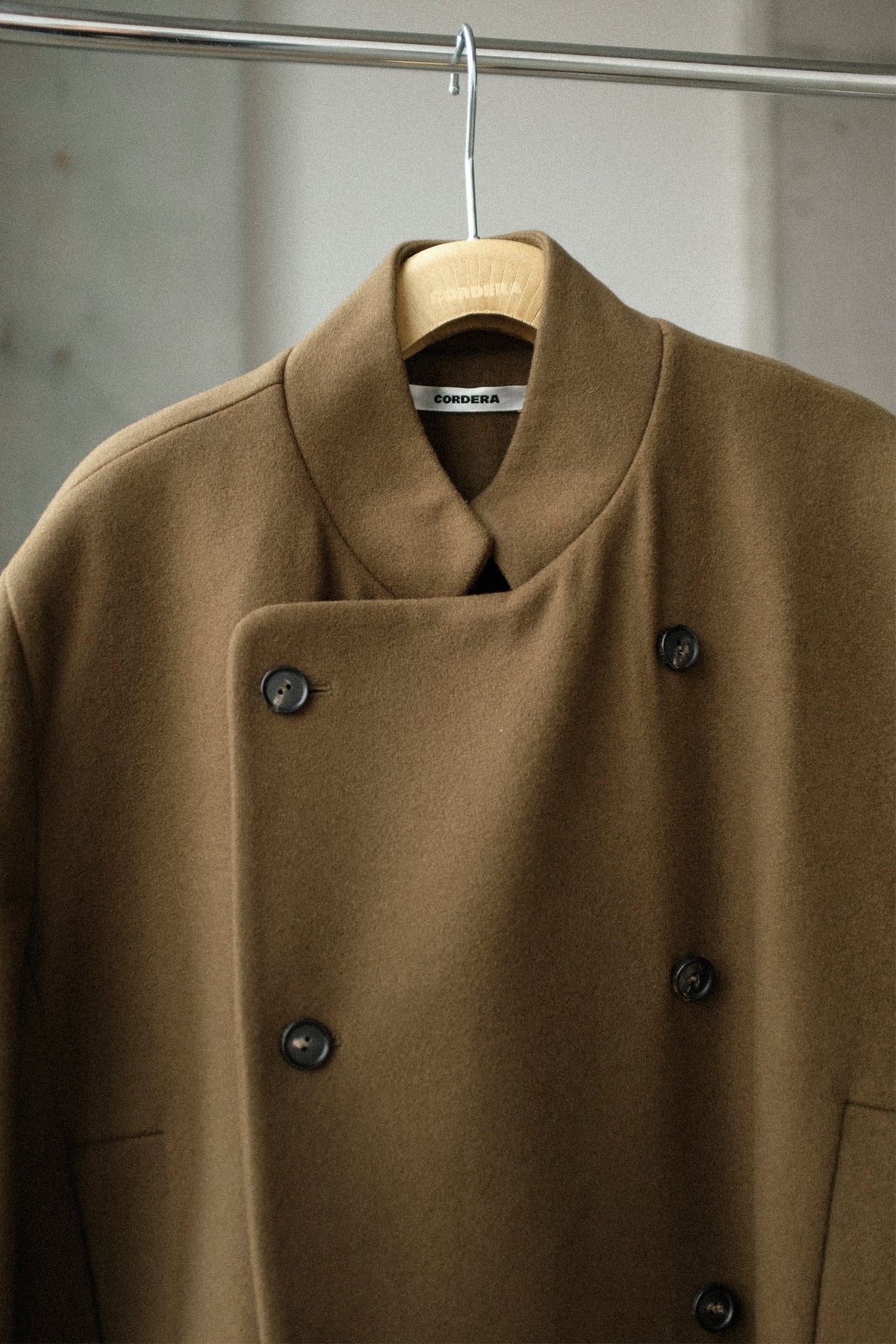 A still image of the Cordera Virgin Wool Long Coat hanging from a silver rack.