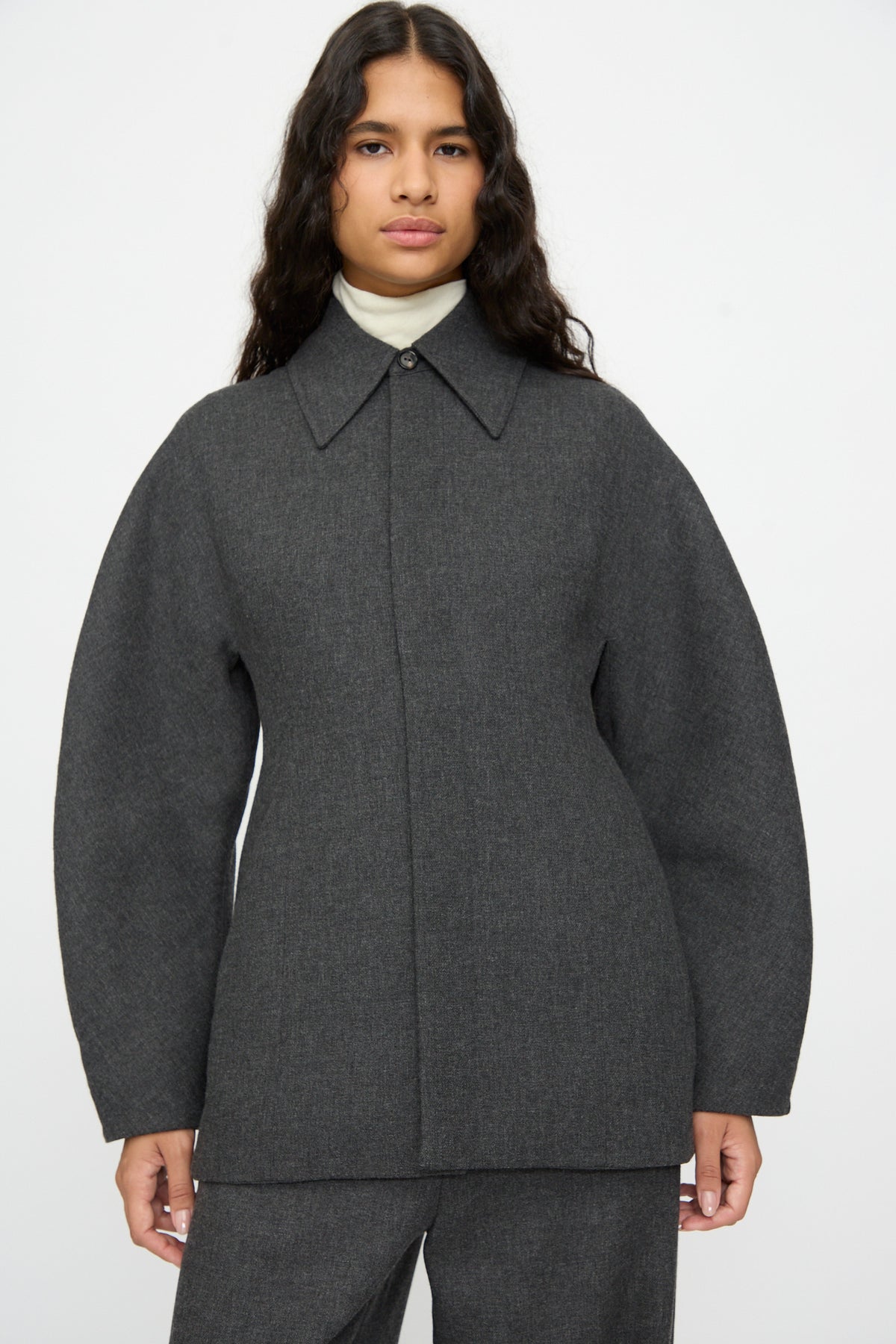 A person wearing a Cordera Wool Overshirt in Grey over a cream-colored turtleneck.