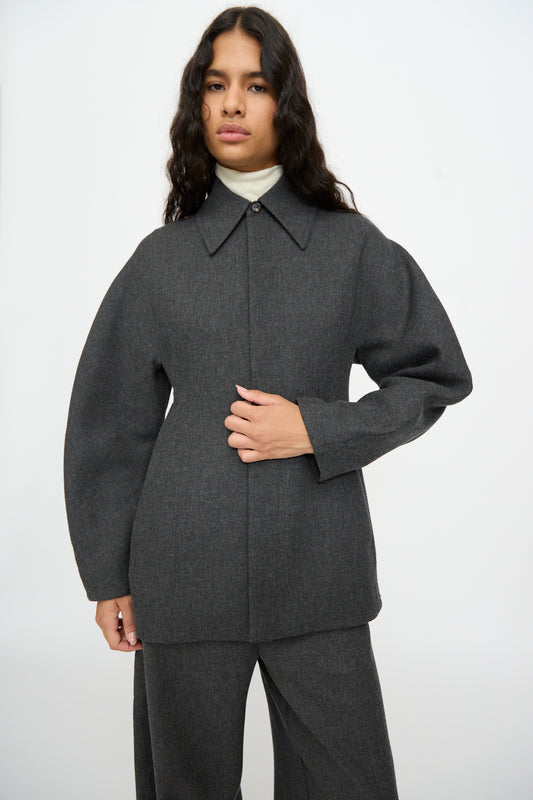 A person wearing a grey, relaxed fit Cordera Wool Overshirt in Grey over a white turtleneck, featuring long, wide sleeves and a high collar.