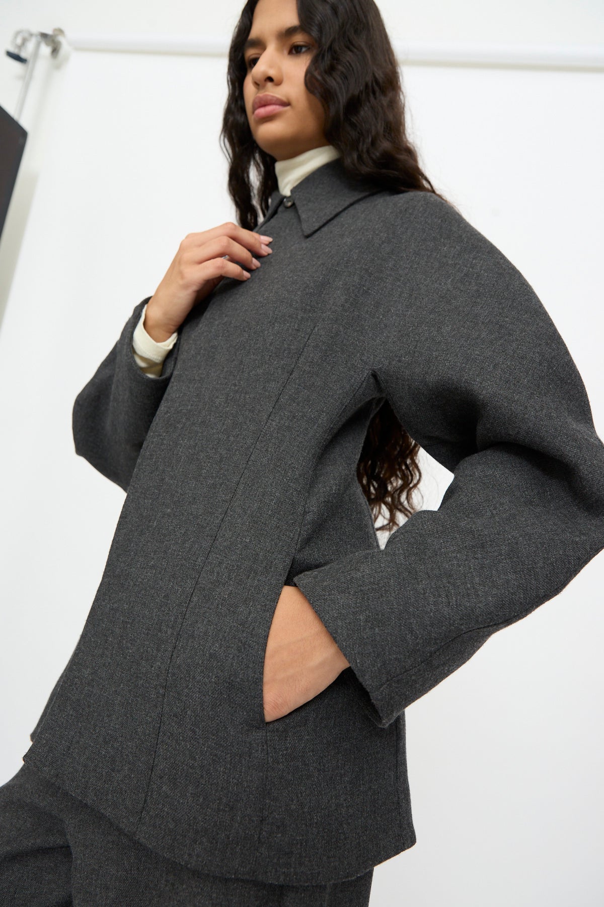 A person wearing a Cordera Wool Overshirt in Grey over a white high-neck top.