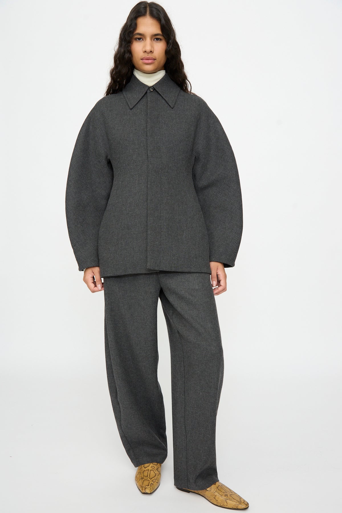 A person wearing a grey Cordera Wool Overshirt in a relaxed-fit with wide sleeves and matching wide-leg trousers.