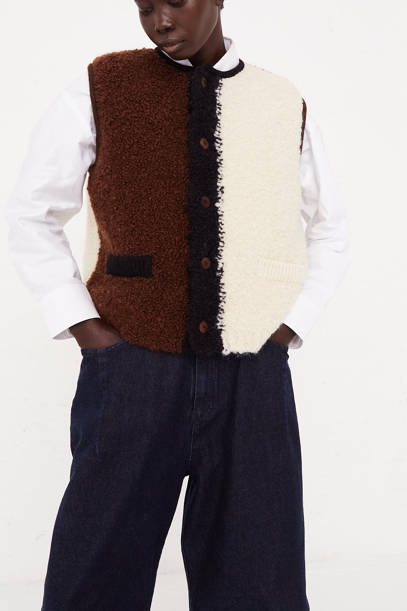 A model wearing a knit waistcoat in a wool and mohair blend. Features a front button closure, banded edges and color block detail. Designed by Cordera - Oroboro Store