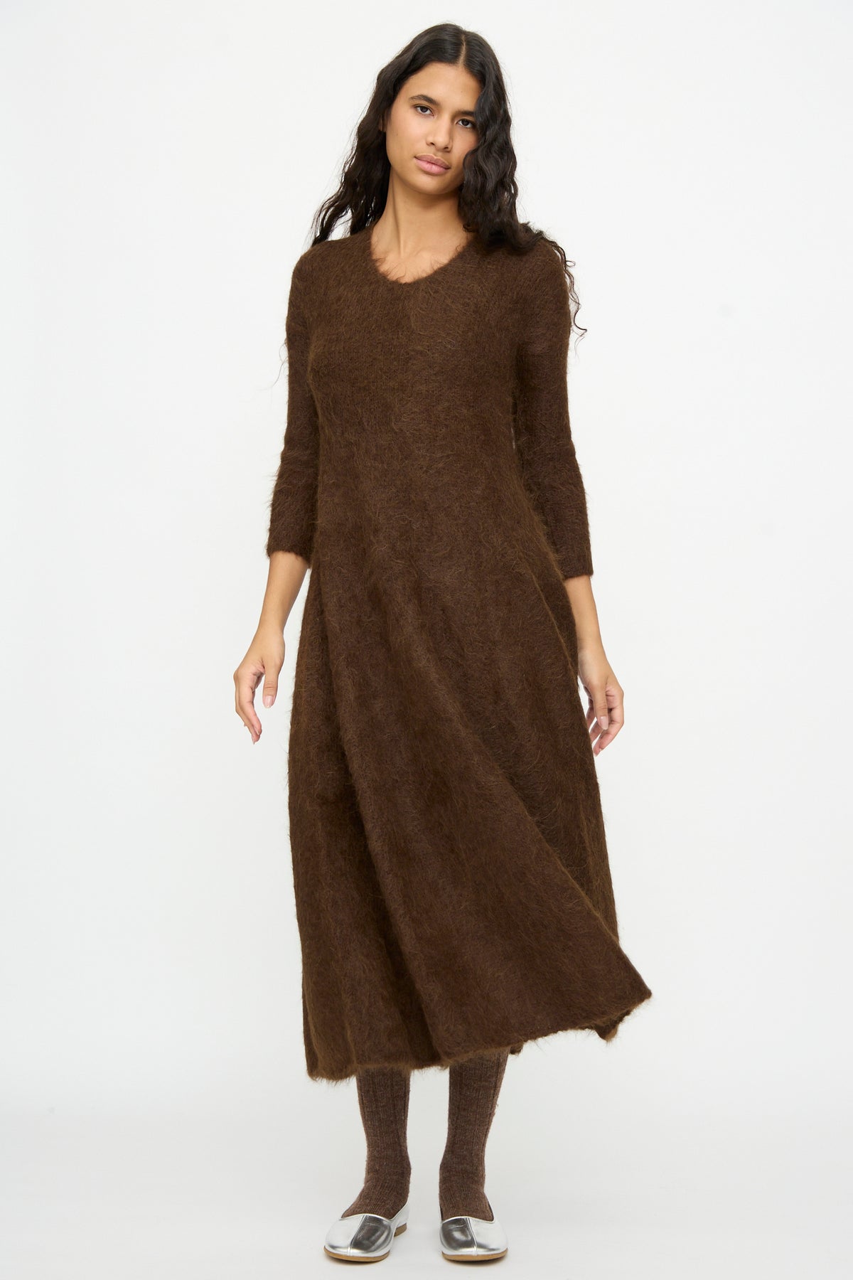 A woman wearing a brown fuzzy Cosmic Wonder Alpaca Knitted Evening Dress, matching brown tights, and metallic silver flats.
