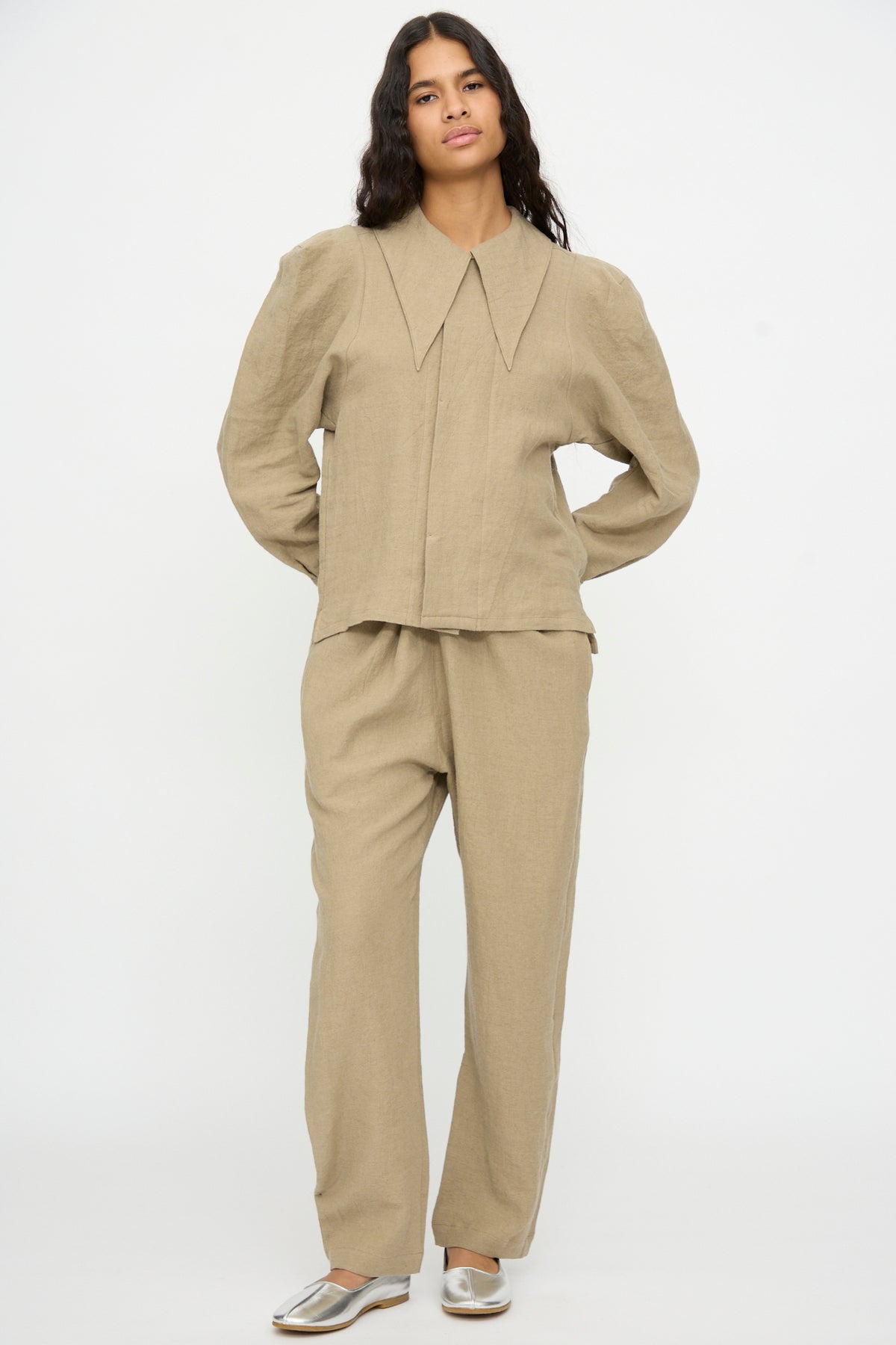 Person wearing a beige Cosmic Wonder Band Collar Shirt with a pointed collar and matching trousers, paired with silver shoes.