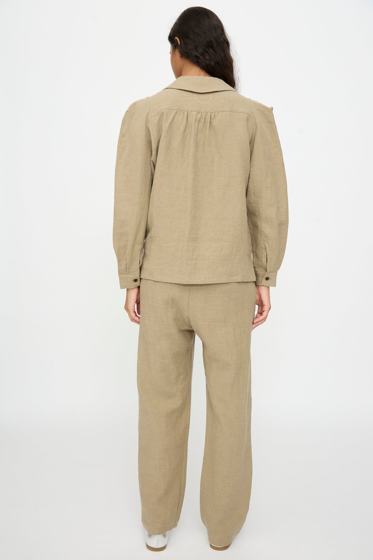 Back view of a person wearing a Cosmic Wonder Band Collar Shirt in beige with matching trousers.