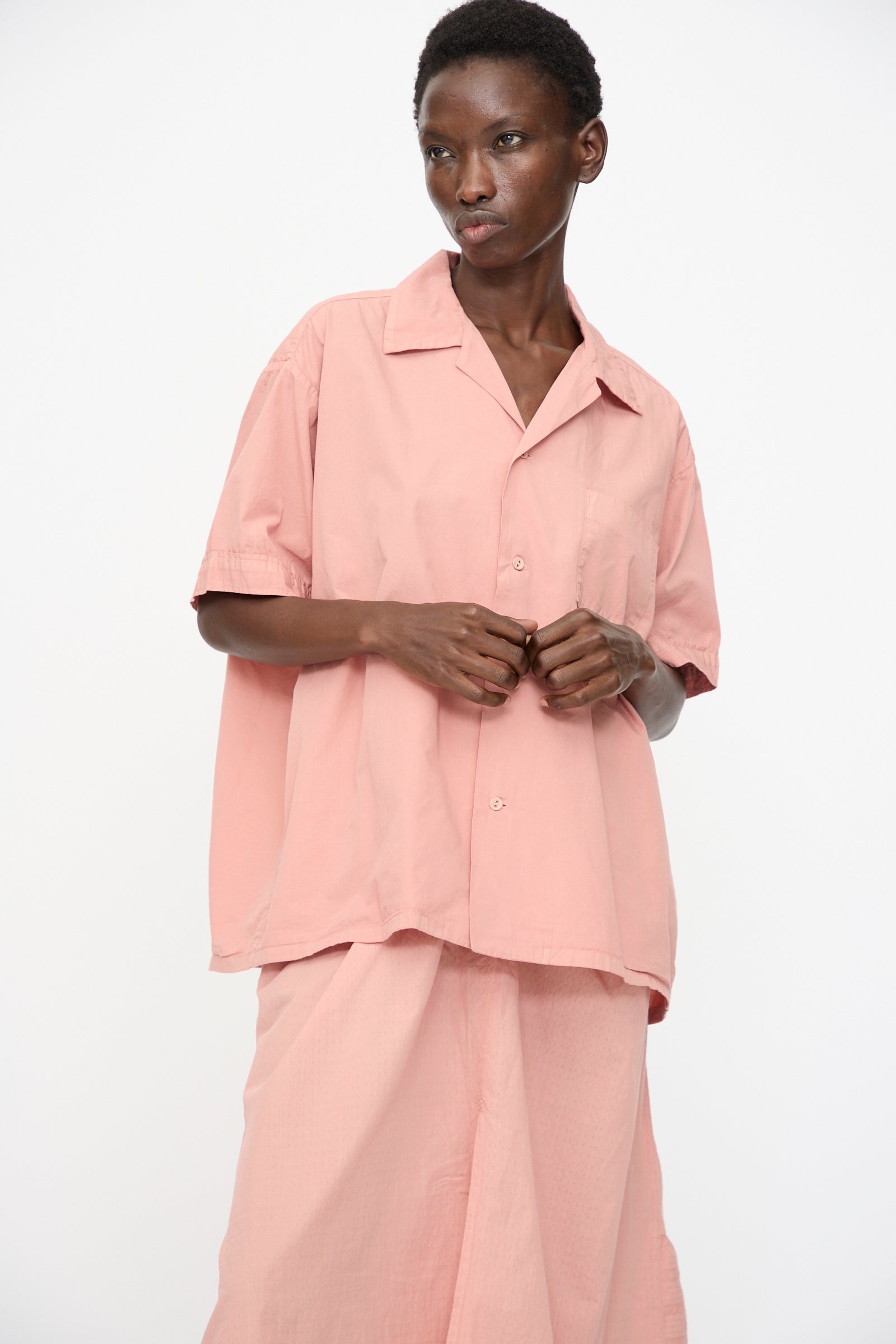 A person wears the Cosmic Wonder Cotton Broadcloth Open Collar Shirt in Rose Crystal, styled with matching wide-legged pants, standing against a plain white background.