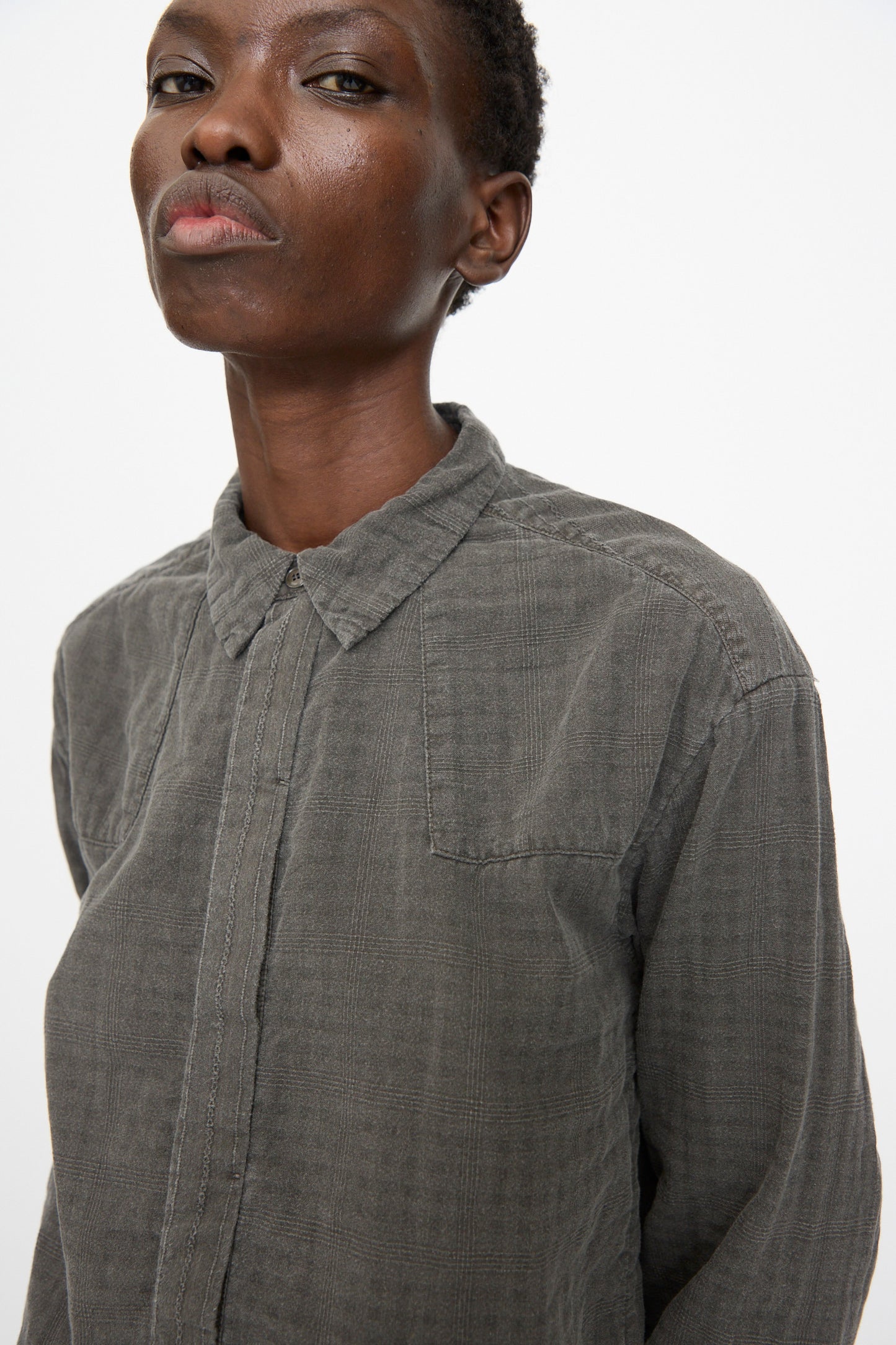 Someone wearing the Cosmic Wonder Double Gauze Check Country Shirt in Dark Sumi stands against a plain, light background.