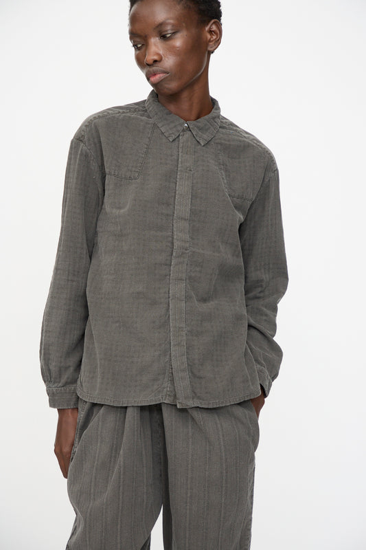 A person wears the Cosmic Wonder Double Gauze Check Country Shirt in Dark Sumi, standing against a plain white background with one hand in their pocket.