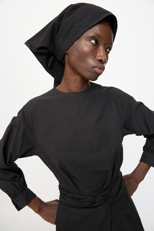Model wears the Cosmic Wonder Double Gauze Check Hair Scarf in Black, styled with a black long-sleeve top, standing hands on hips and looking to the side against a plain background.