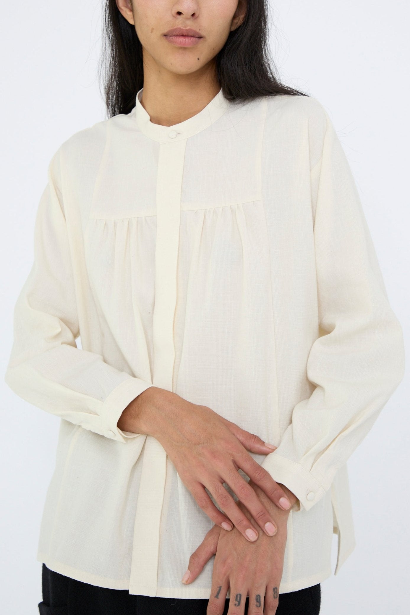 A person with long dark hair is wearing the Light Merino, Linen and Cotton Glencheck Elegant Gathered Shirt in White by Cosmic Wonder. The background is plain white.