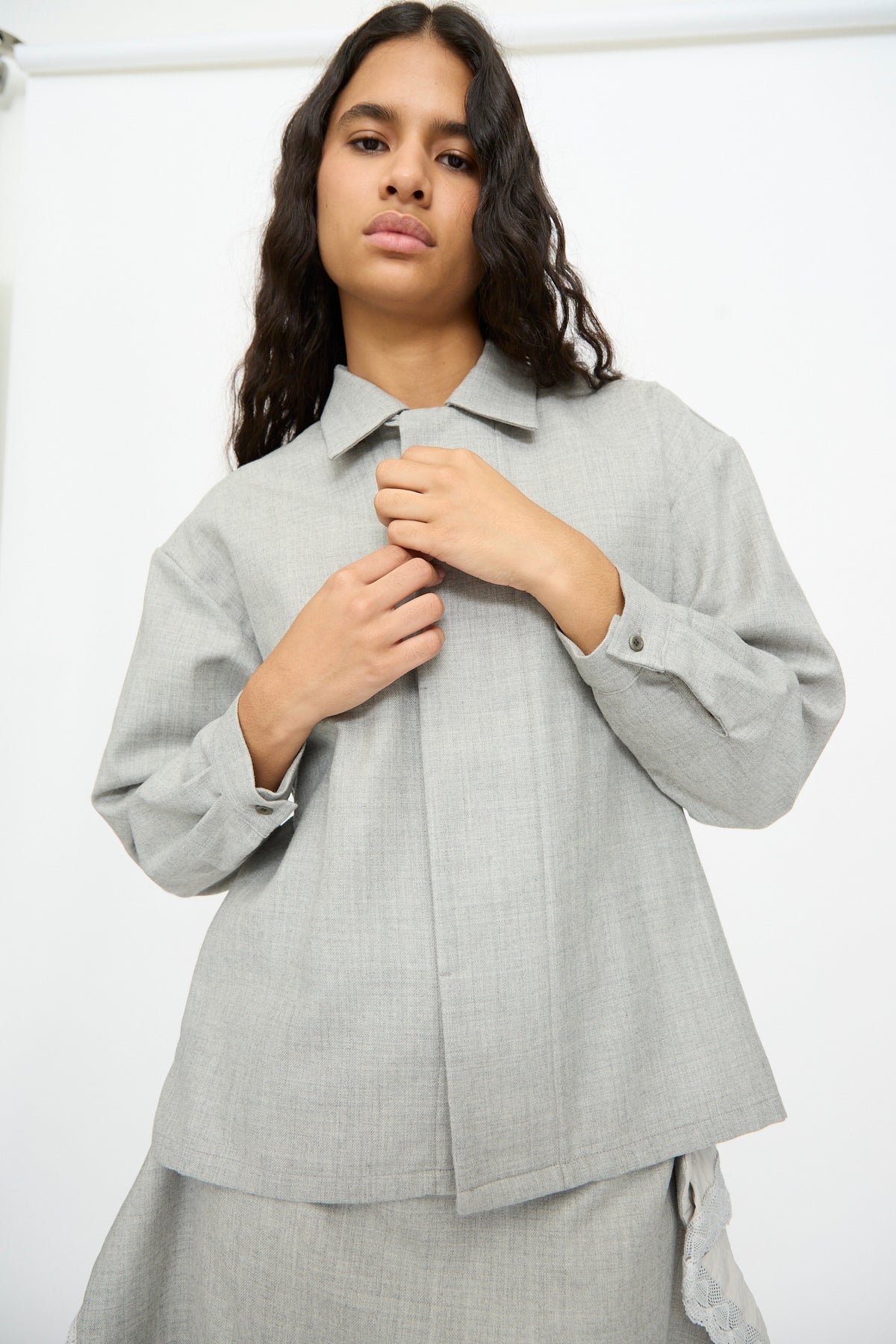A person wearing a Cosmic Wonder Nostalgic Artist’s Camp Collar Shirt in Gray, a long-sleeved, gray wool button-up shirt with a camp collar.