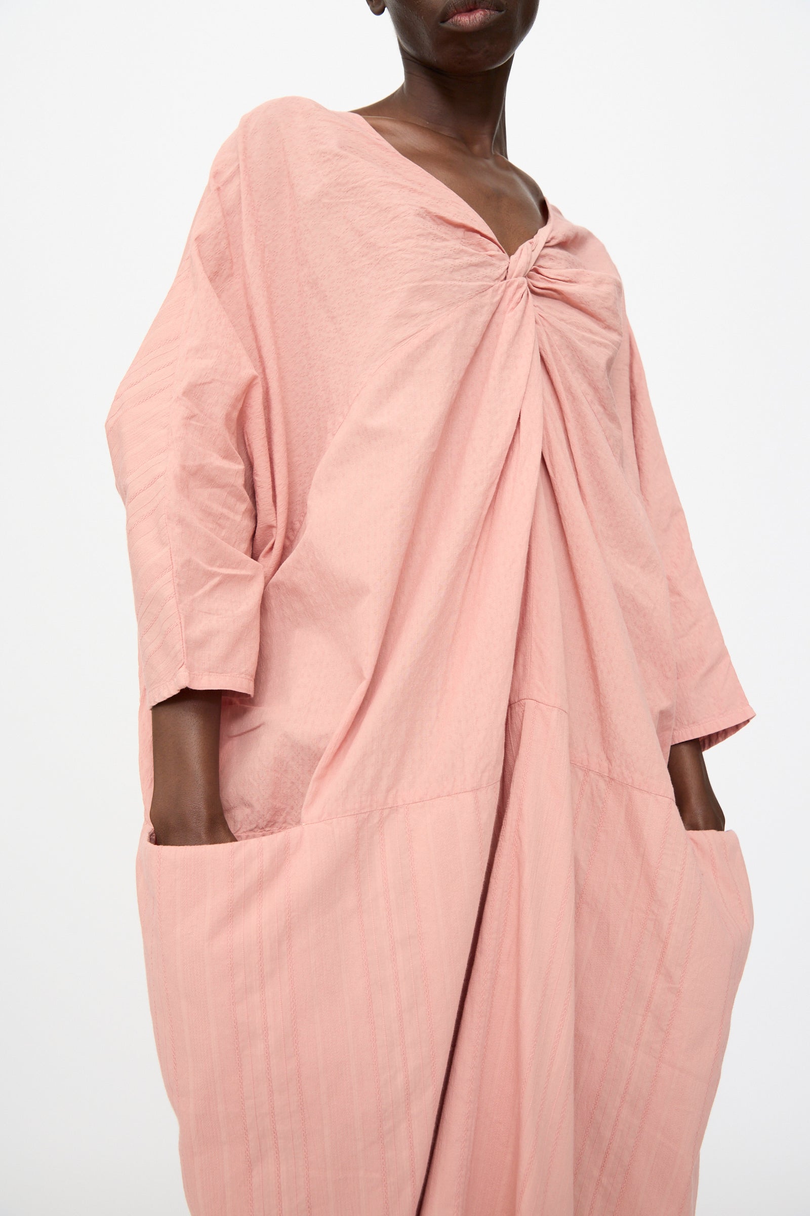 A person models the Cosmic Wonder Stripe Combination Twisted Dress in Rose Crystal, a relaxed-fit, Japanese-made dress with gathered neckline detail and side pockets, shown against a plain white background.