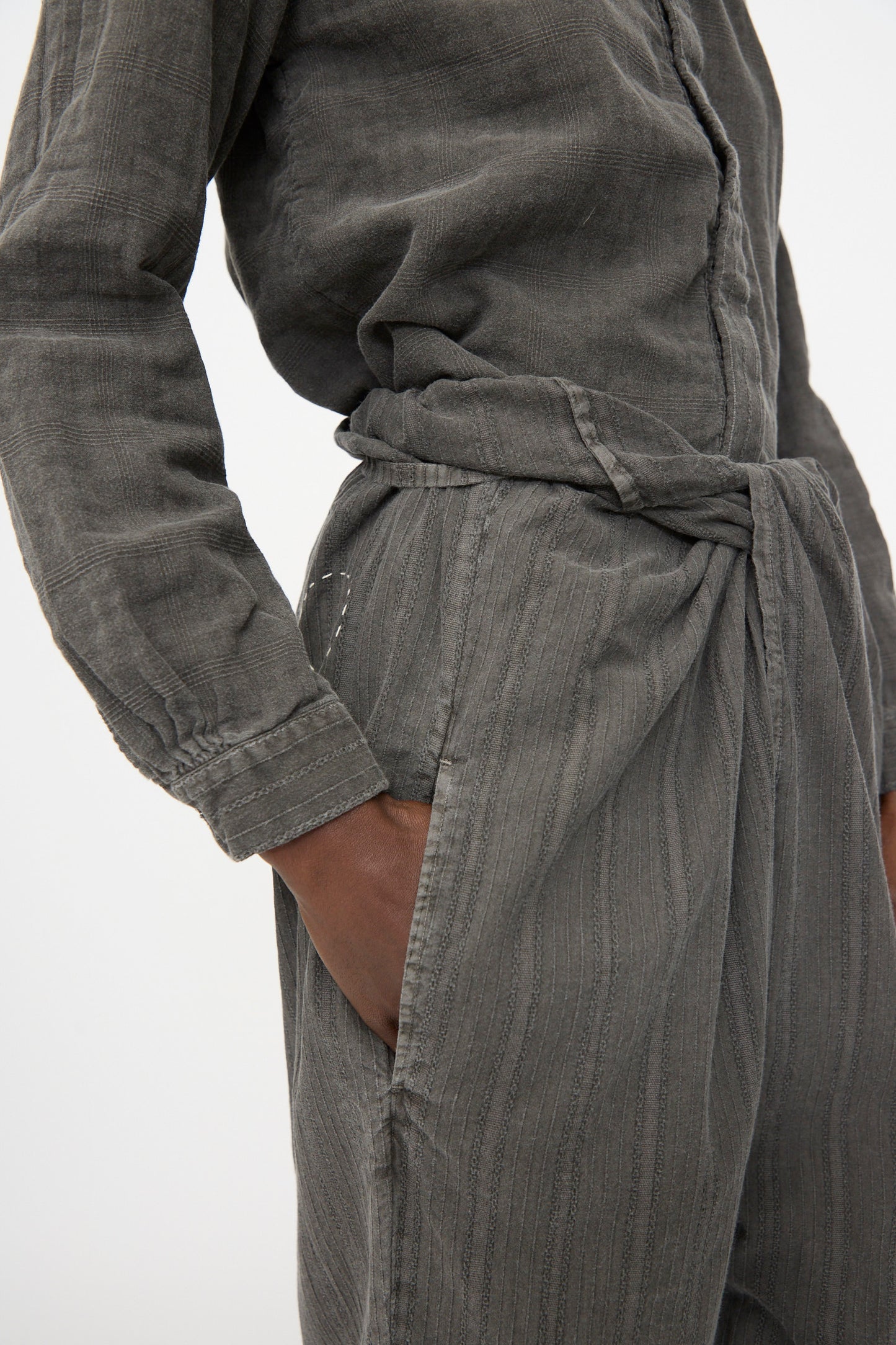 Person wearing Cosmic Wonder's Stripe Combination Wrapped Pant in Dark Sumi, crafted in Japan, hand in pocket, pictured from waist to upper arm.