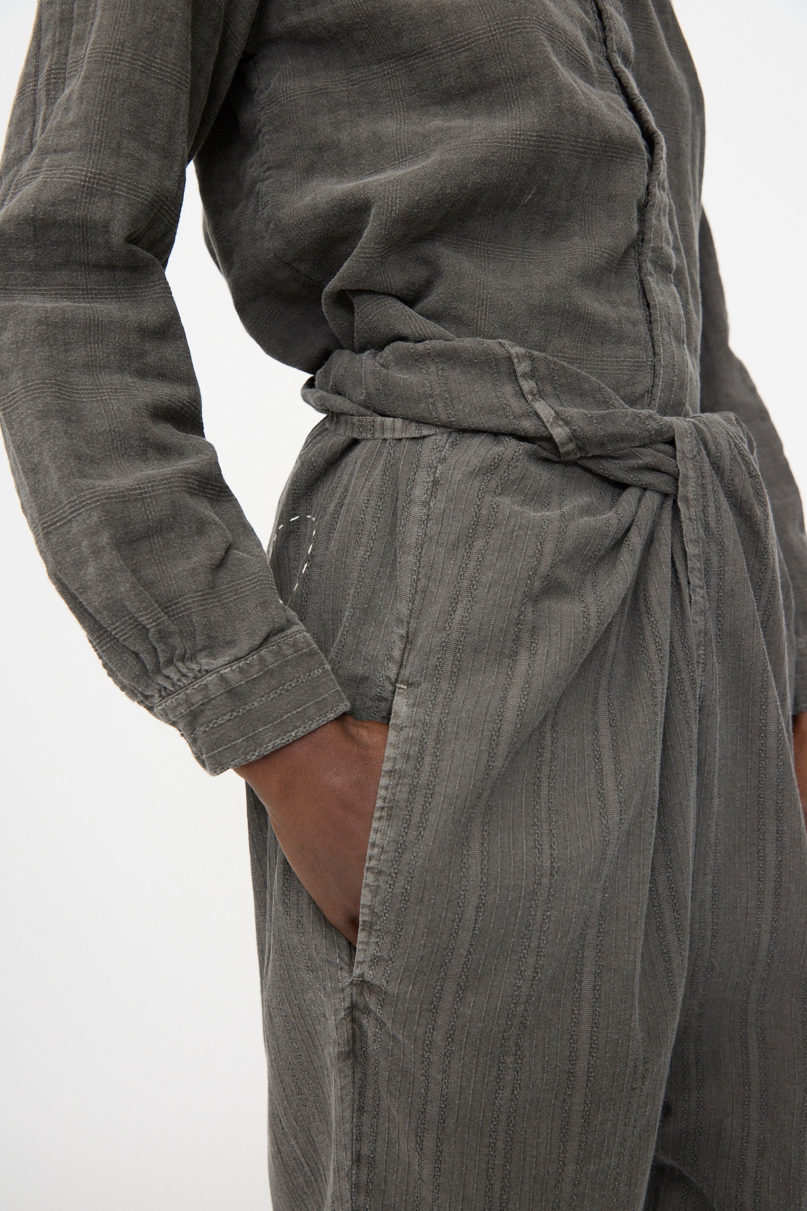 Person wearing Cosmic Wonder's Stripe Combination Wrapped Pant in Dark Sumi, crafted in Japan, hand in pocket, pictured from waist to upper arm.