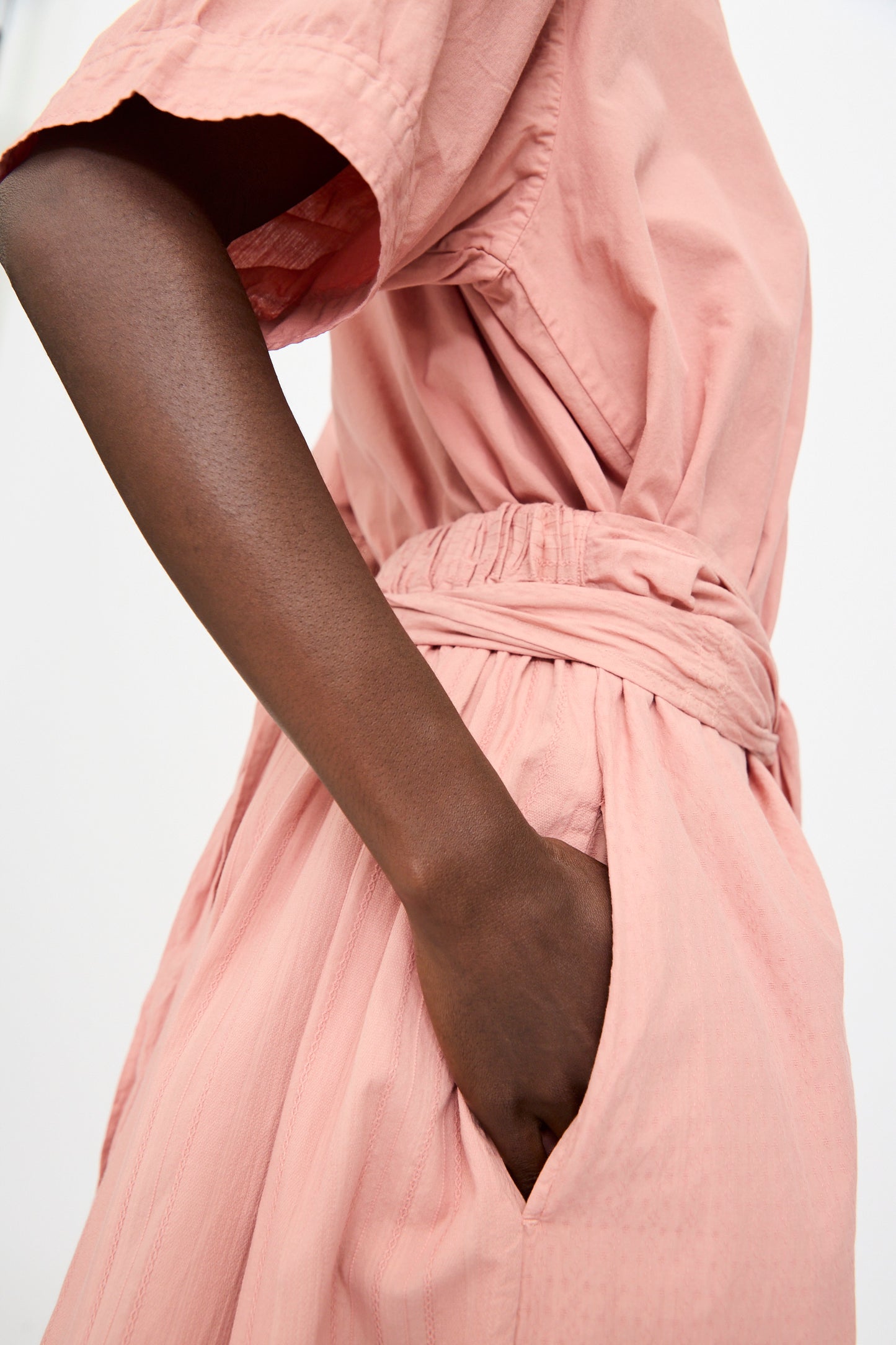 A person wearing the Cosmic Wonder Stripe Combination Wrapped Skirt in Rose Crystal, featuring a gathered waist and side pocket, has one hand tucked casually in the pocket.