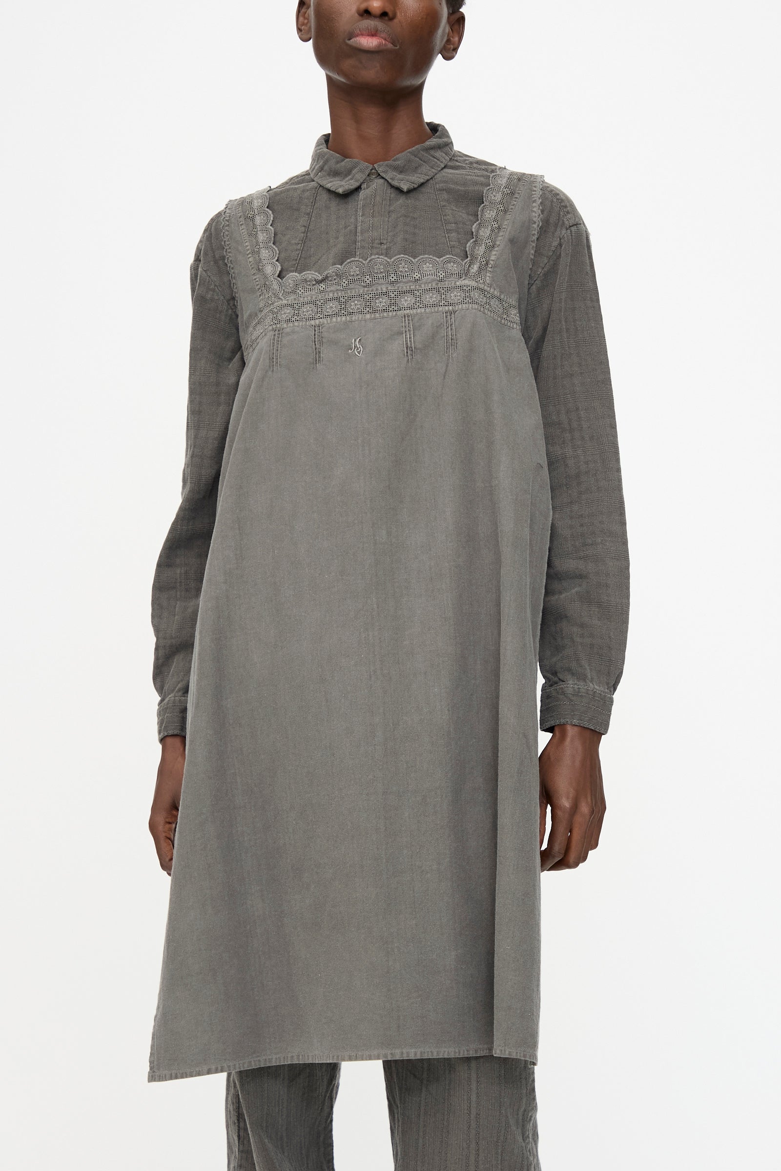 A person wearing the Cosmic Wonder Taskuki Apron in Dark Sumi layered over a long-sleeved collared shirt, styled against a plain white background.