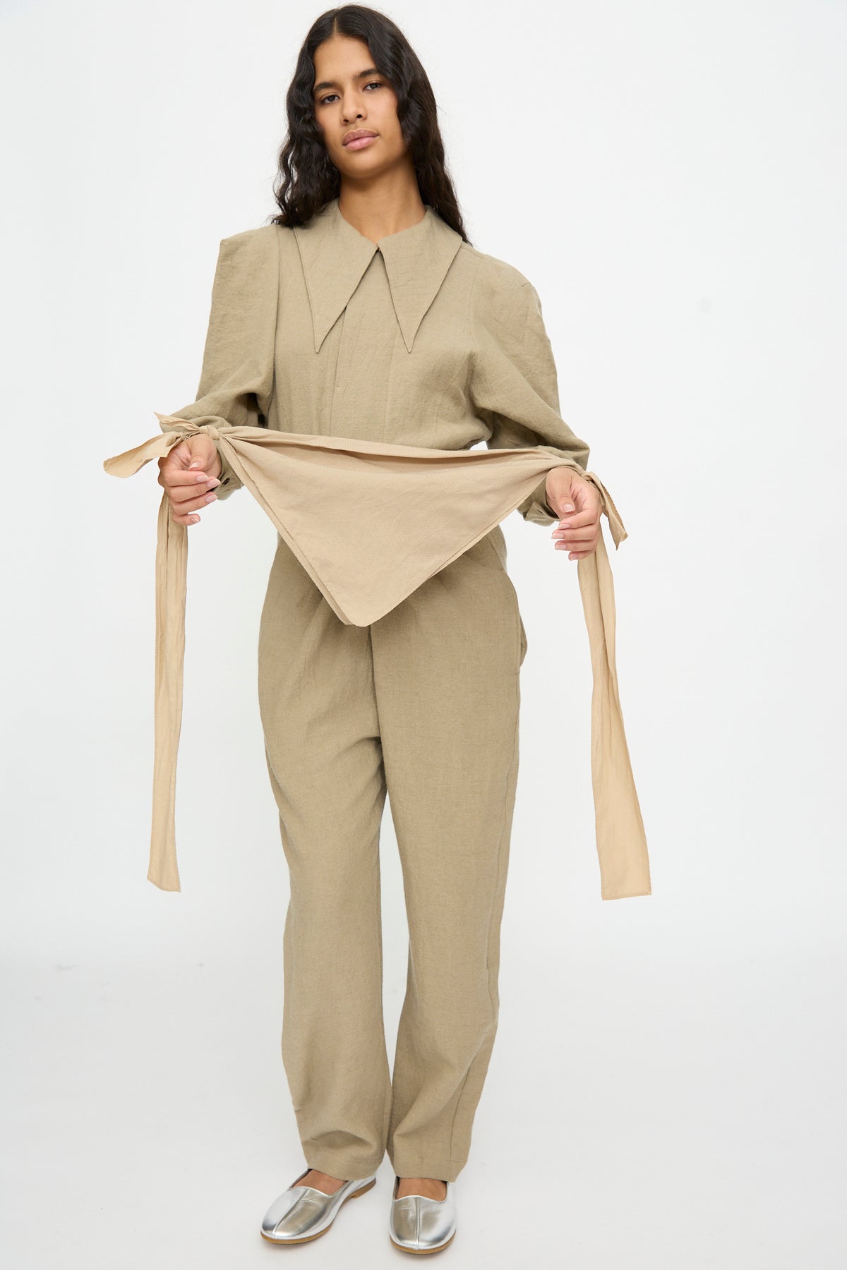 Person wearing a beige jumpsuit with a wide collar, styled with The Farmer’s Star Belt in Amber Light and a polka dot handkerchief tied at their waist.