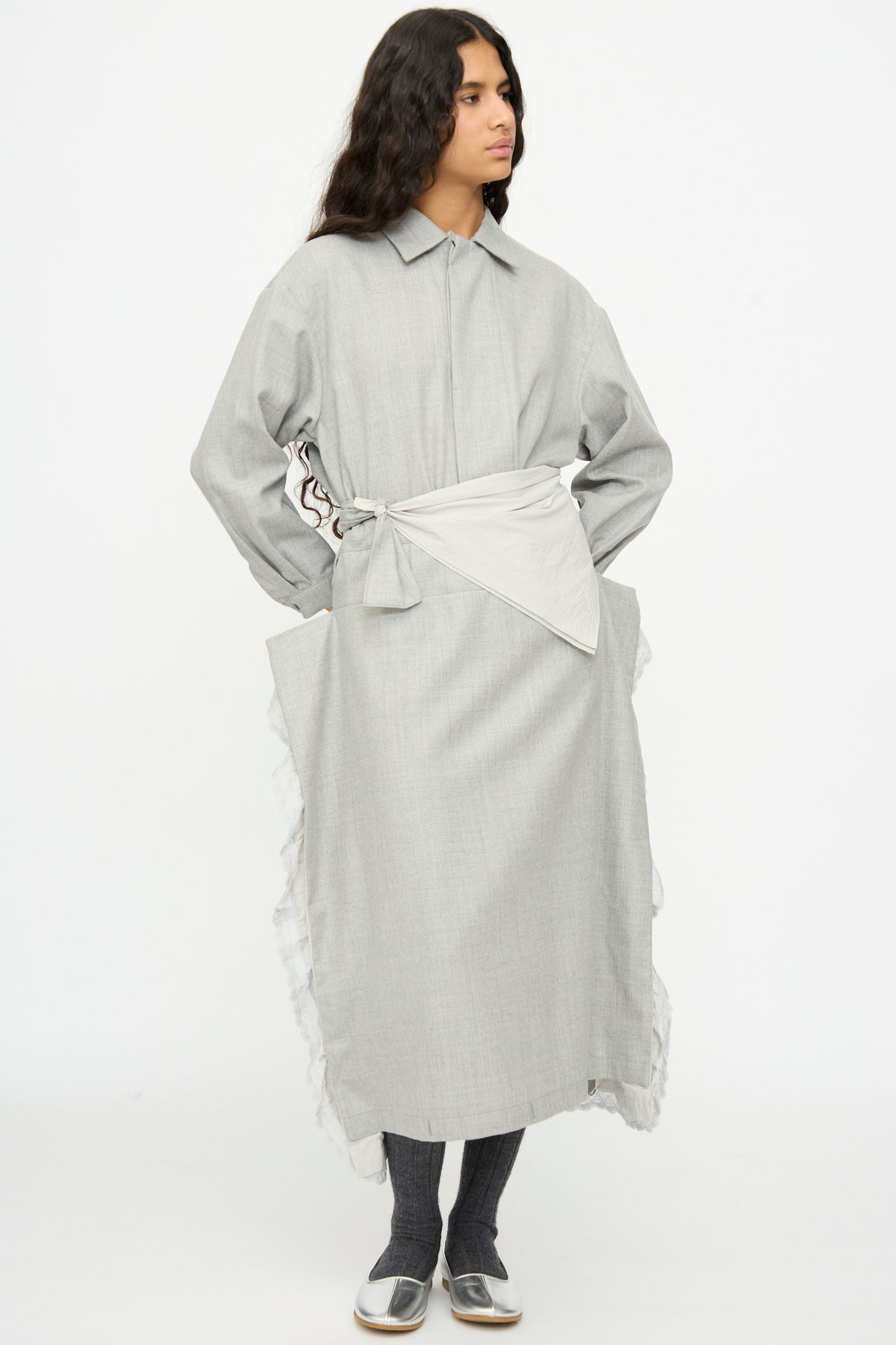A person wears a Cosmic Wonder Nostalgic Painter’s Star Belt in Gray over a long-sleeved gray wool and cotton dress with a layered, asymmetrical handkerchief belt and white ruffled trim.