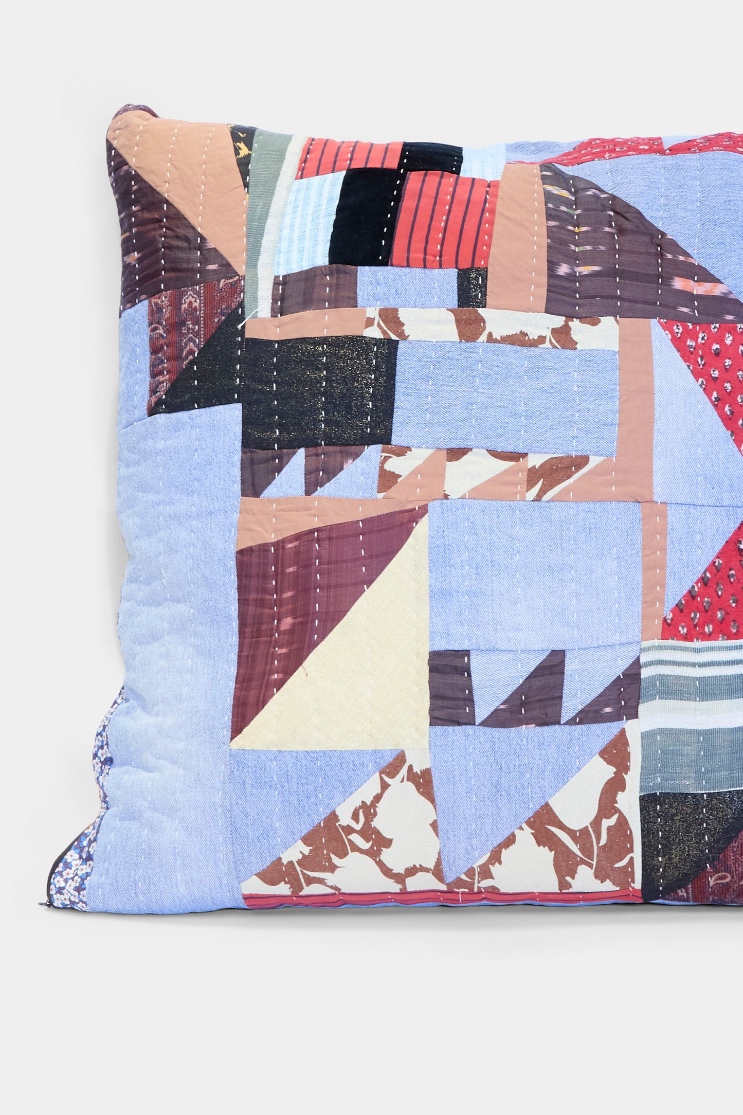 The Patchwork Pillow in Denim and Terracotta Multi II by Counterpane features a rectangular quilted cover in blue, brown, red, black, and cream geometric patterns made from antique cloth. Crafted in California.