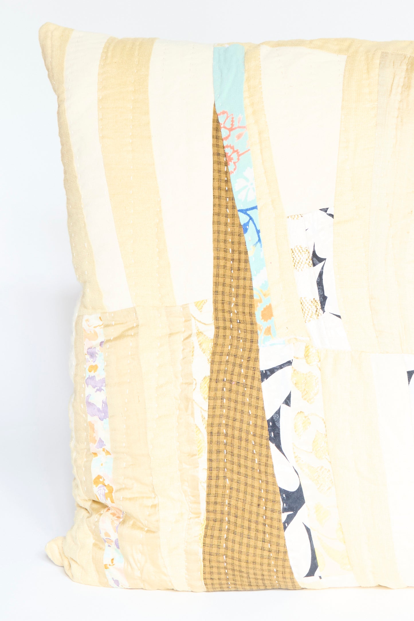 The Patchwork Pillow in Gold Multi II by Counterpane is a square quilted throw pillow featuring a patchwork design with antique found cloth in cream, brown, yellow, blue, and gold multi patterns.