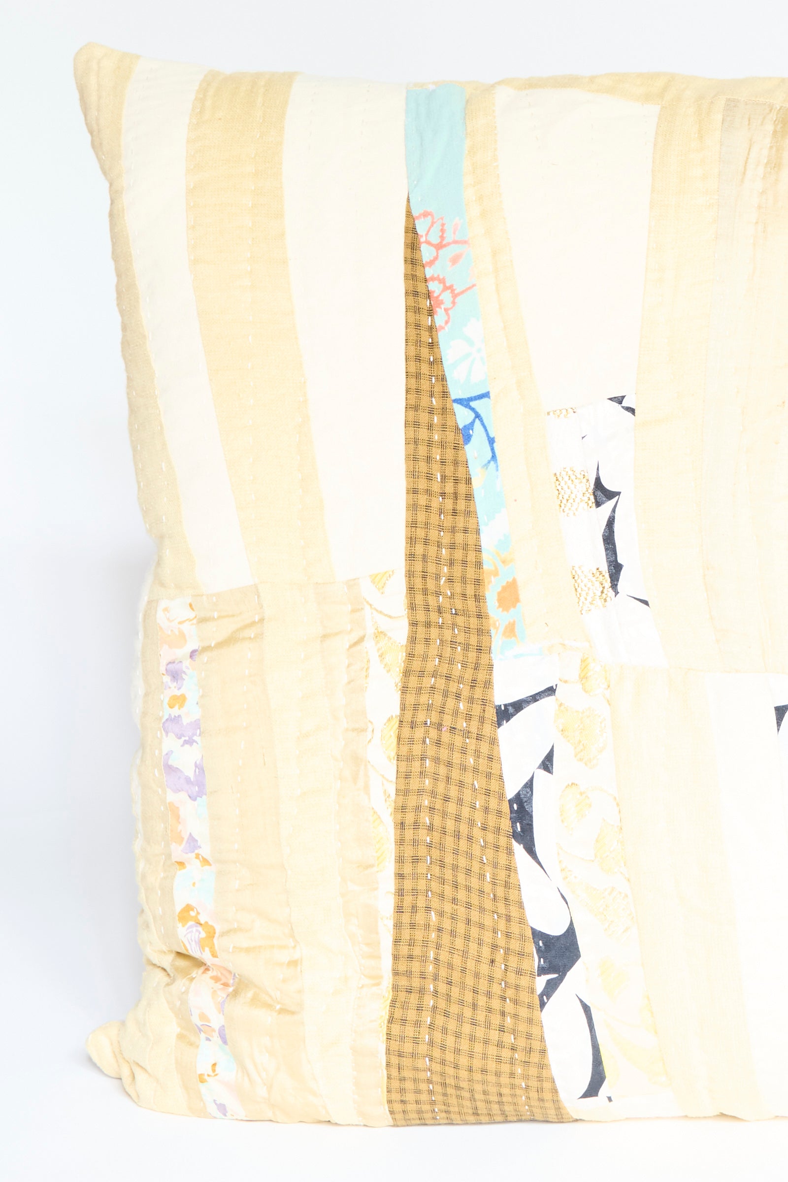 The Patchwork Pillow in Gold Multi II by Counterpane is a square quilted throw pillow featuring a patchwork design with antique found cloth in cream, brown, yellow, blue, and gold multi patterns.