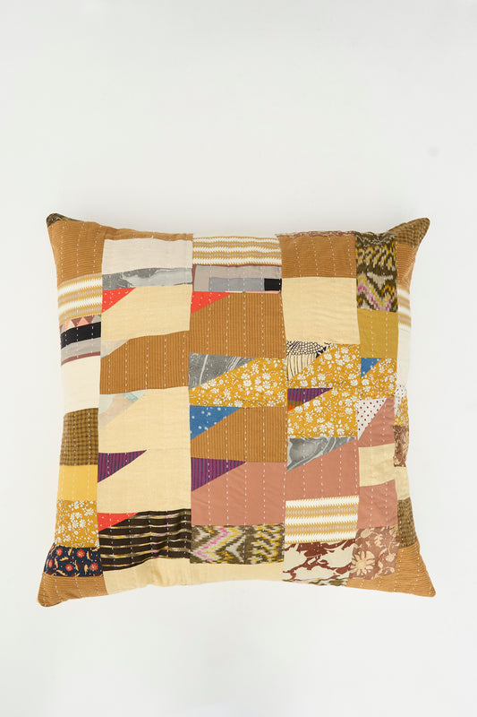 The Patchwork Pillow in Earth Multi I by Counterpane is a square quilted throw pillow featuring a patchwork design in yellow, brown, cream, and patterned fabrics crafted from antique cloth. Made in California, this piece is photographed on a plain white background.