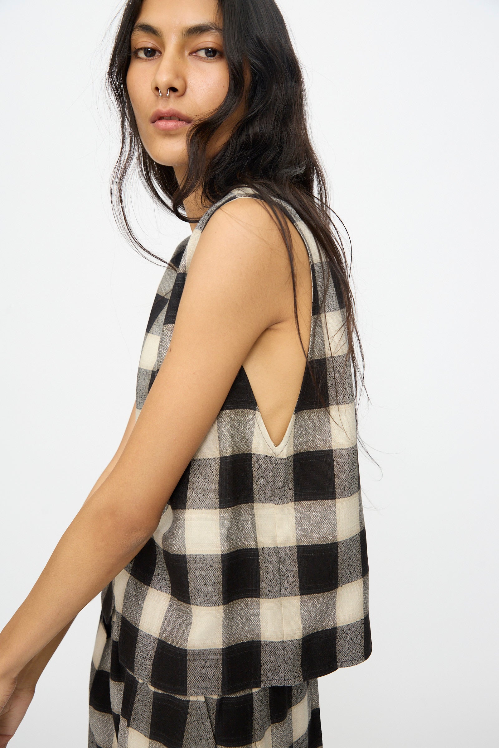 A person with long dark hair wears the Cristaseya Button Down Vest in Black and Cream Checks, standing against a plain white background.