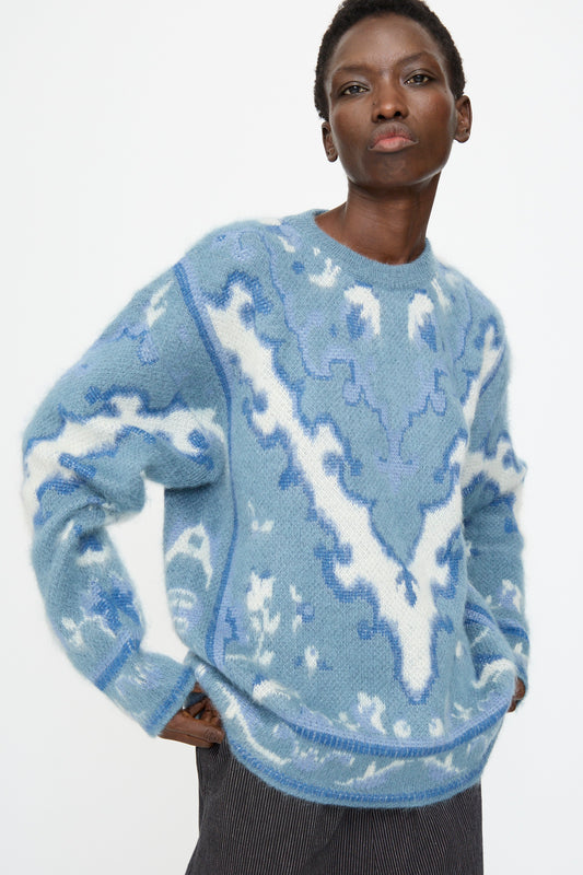 Model wears the Cristaseya Cashmere Oversized Carpet Sweater in Blue and White, paired with dark pinstripe pants, set against a plain background.