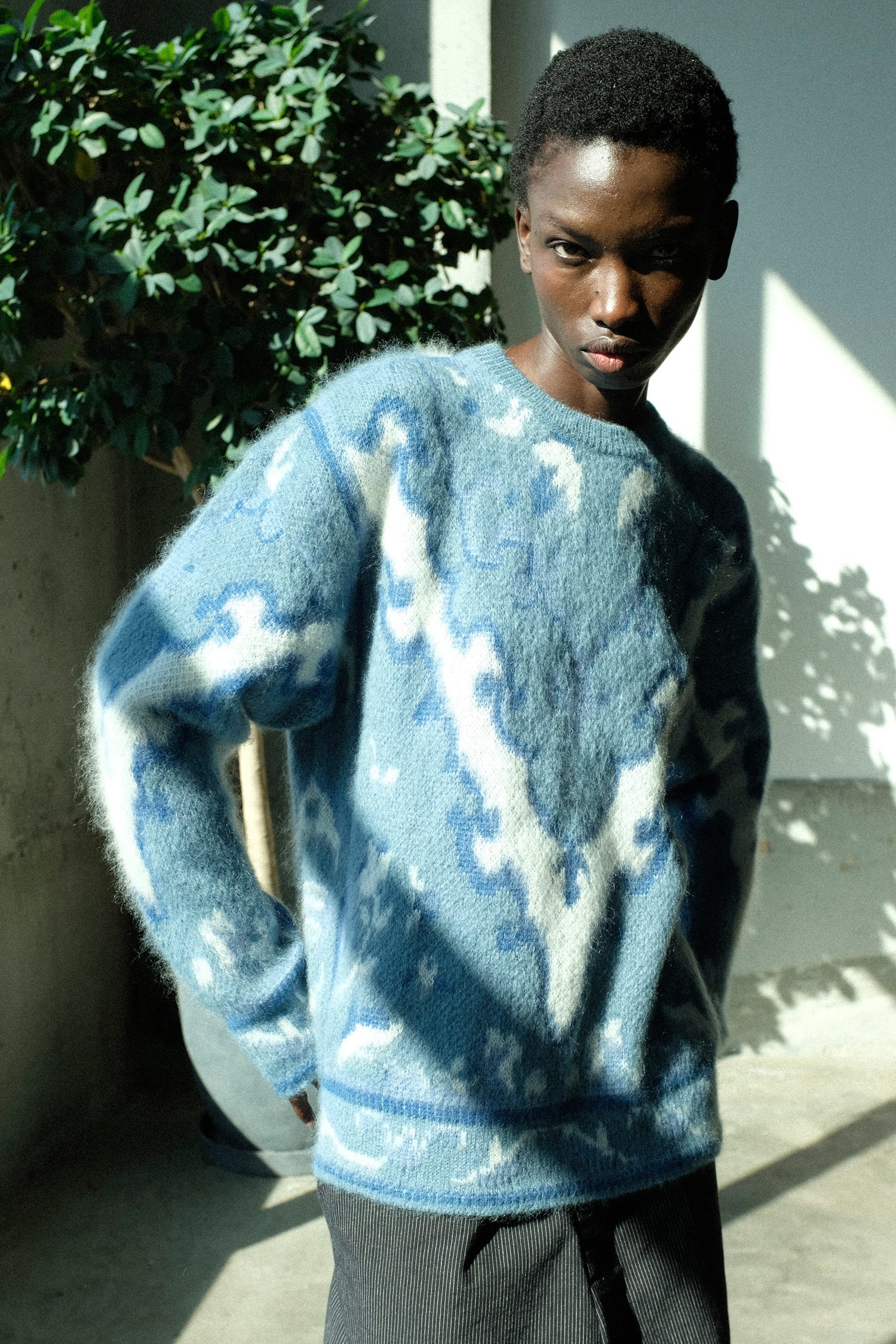 Person wearing a blue and white patterned sweater standing outdoors.