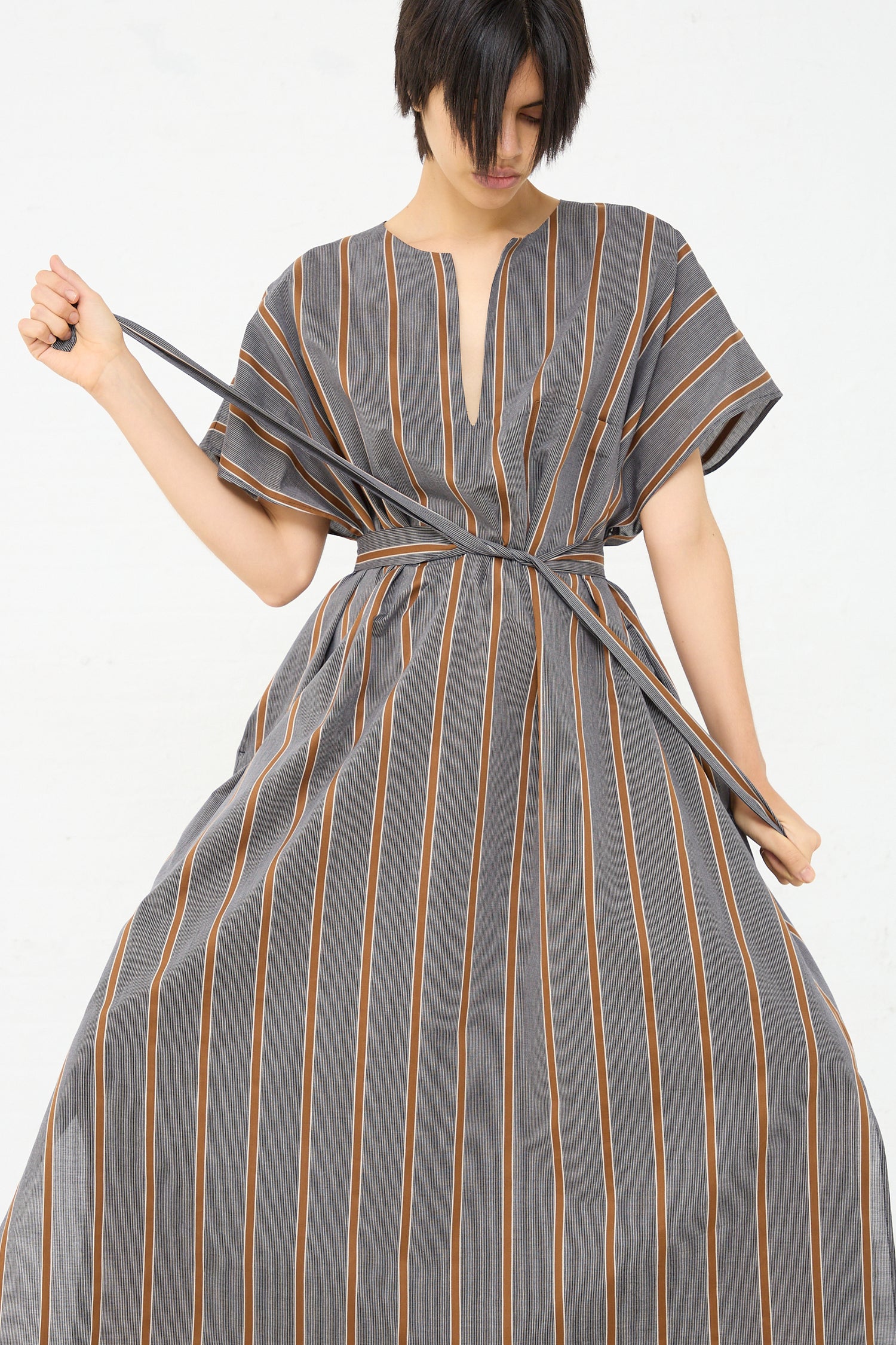 The model is wearing an oversized caftan with a stripe pattern by Cristaseya.